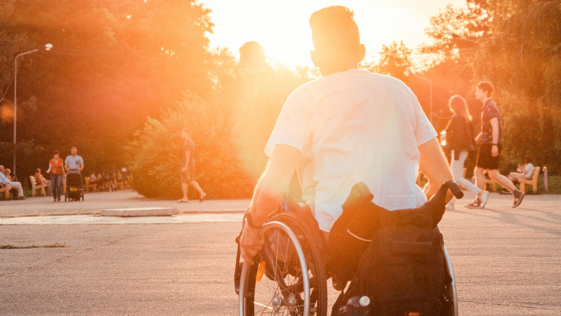 Man in a wheelchair basking in the warm sunset outdoors, symbolizing freedom and accessibility.