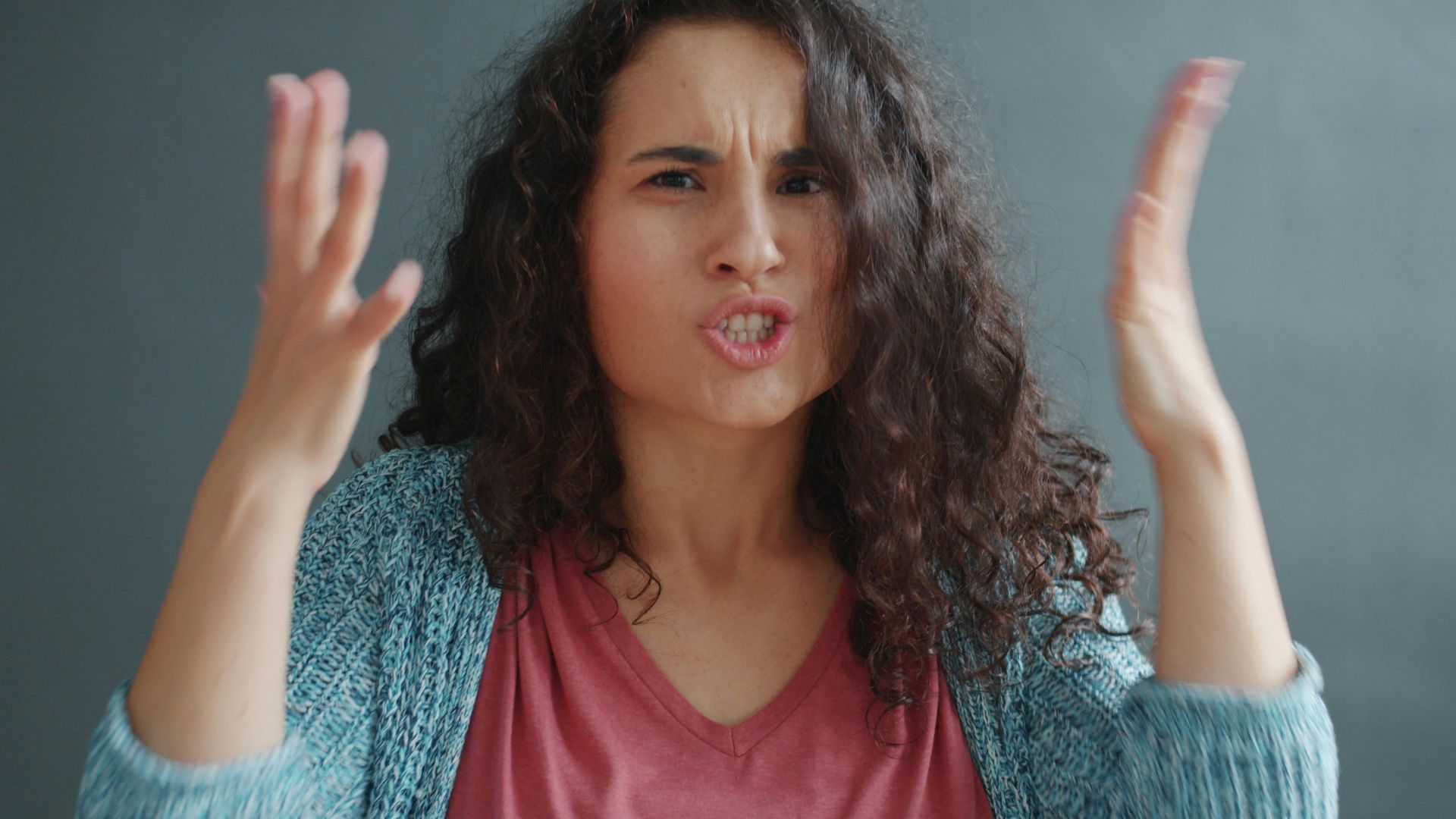 Young woman expressing emotions with animated gestures indoors.