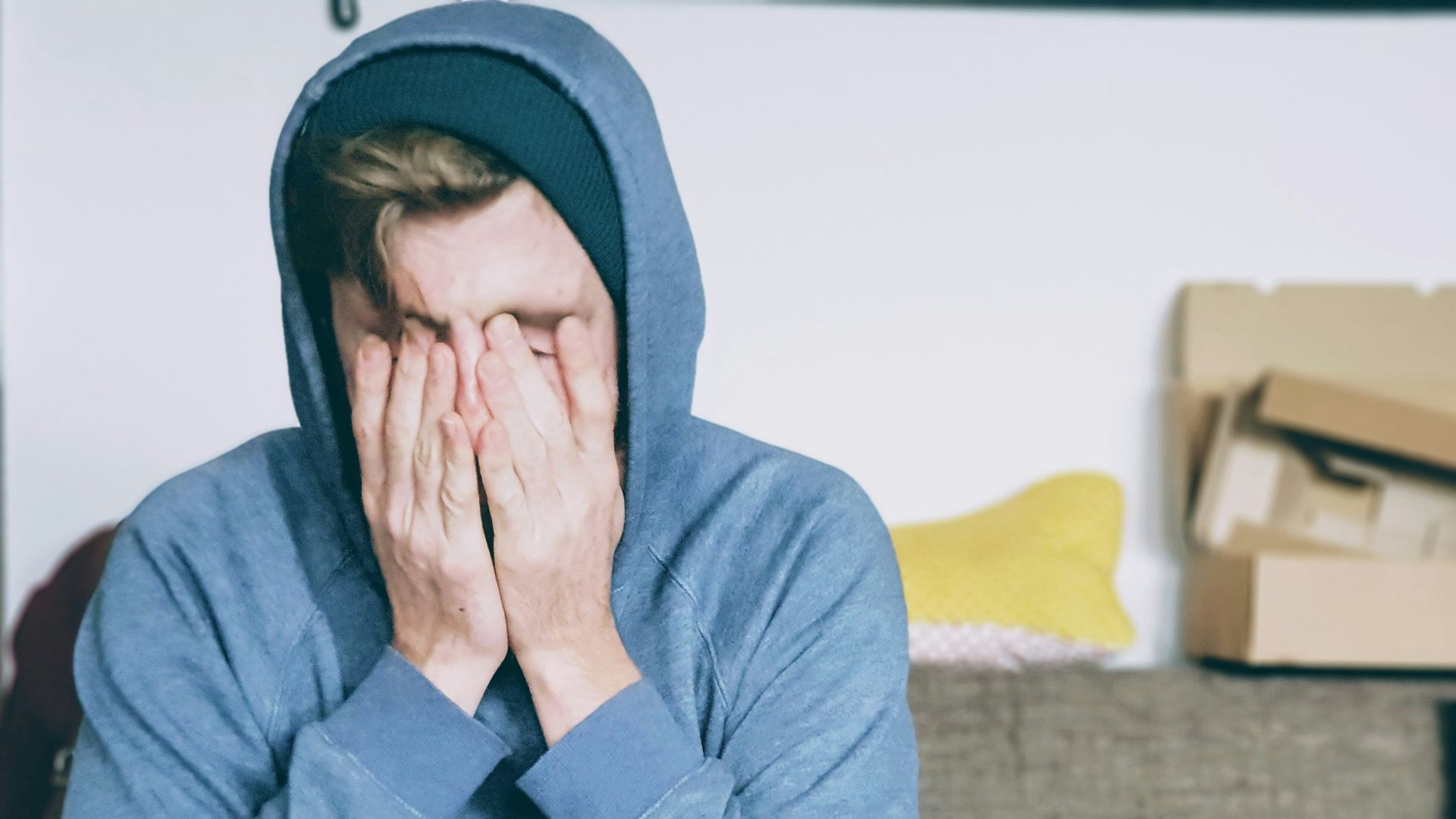 man covering face with both hands while sitting on bench