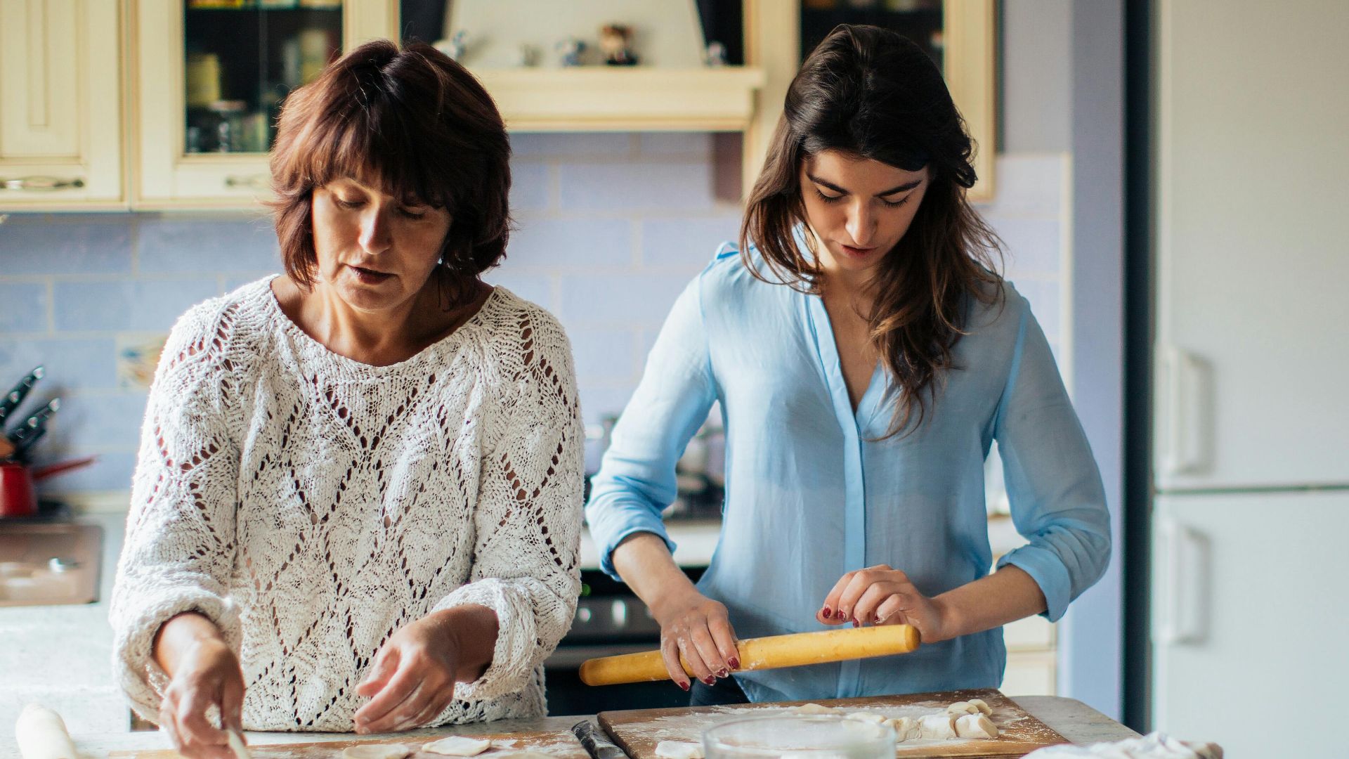 Mother and daughter making traditional Russian pelmeni in a cozy kitchen setting.