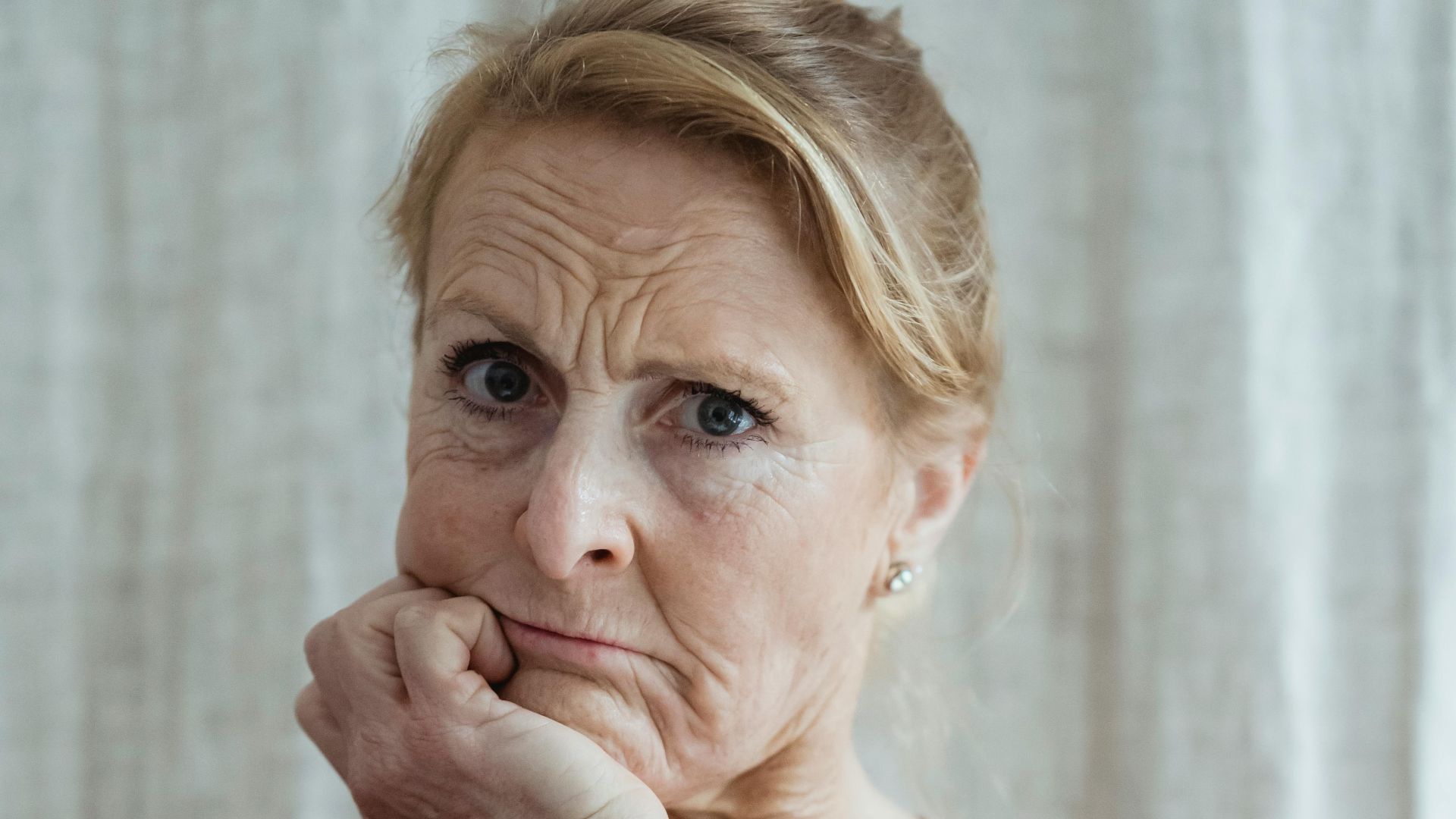 Portrait of a serious senior woman in a thoughtful pose indoors.