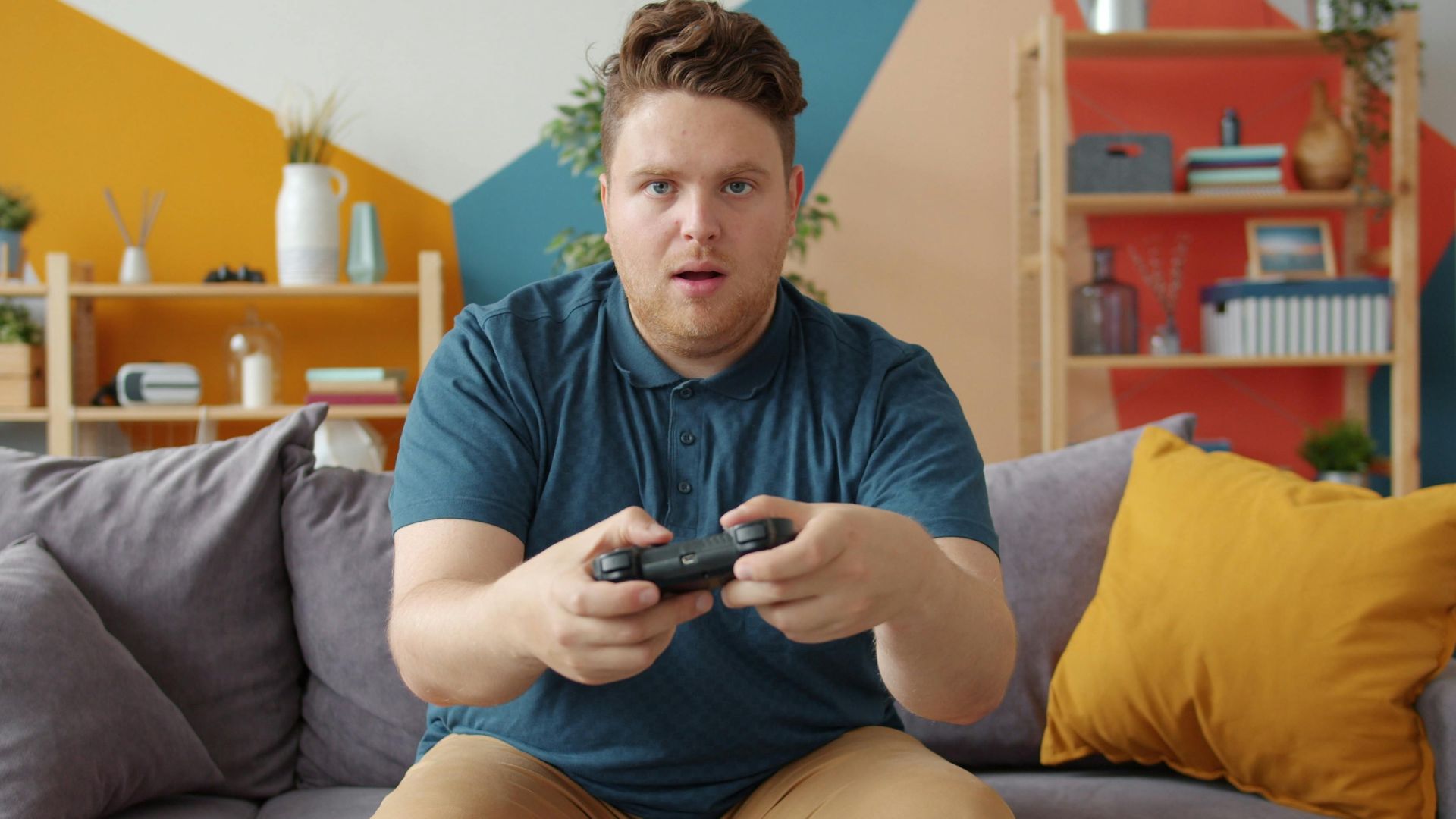 A young man intensely playing video games in a modern living room setting.