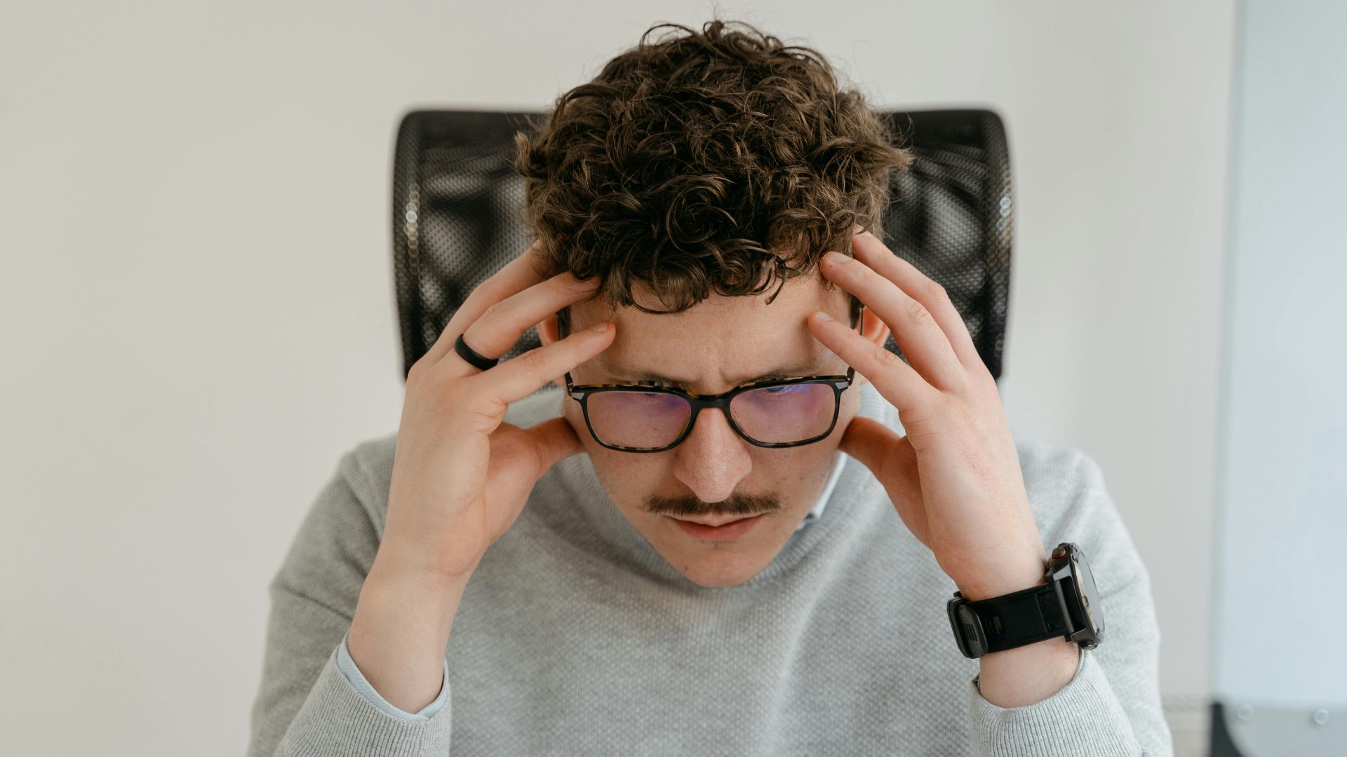 A serious businessman focusing intently on his work, using a laptop indoors.