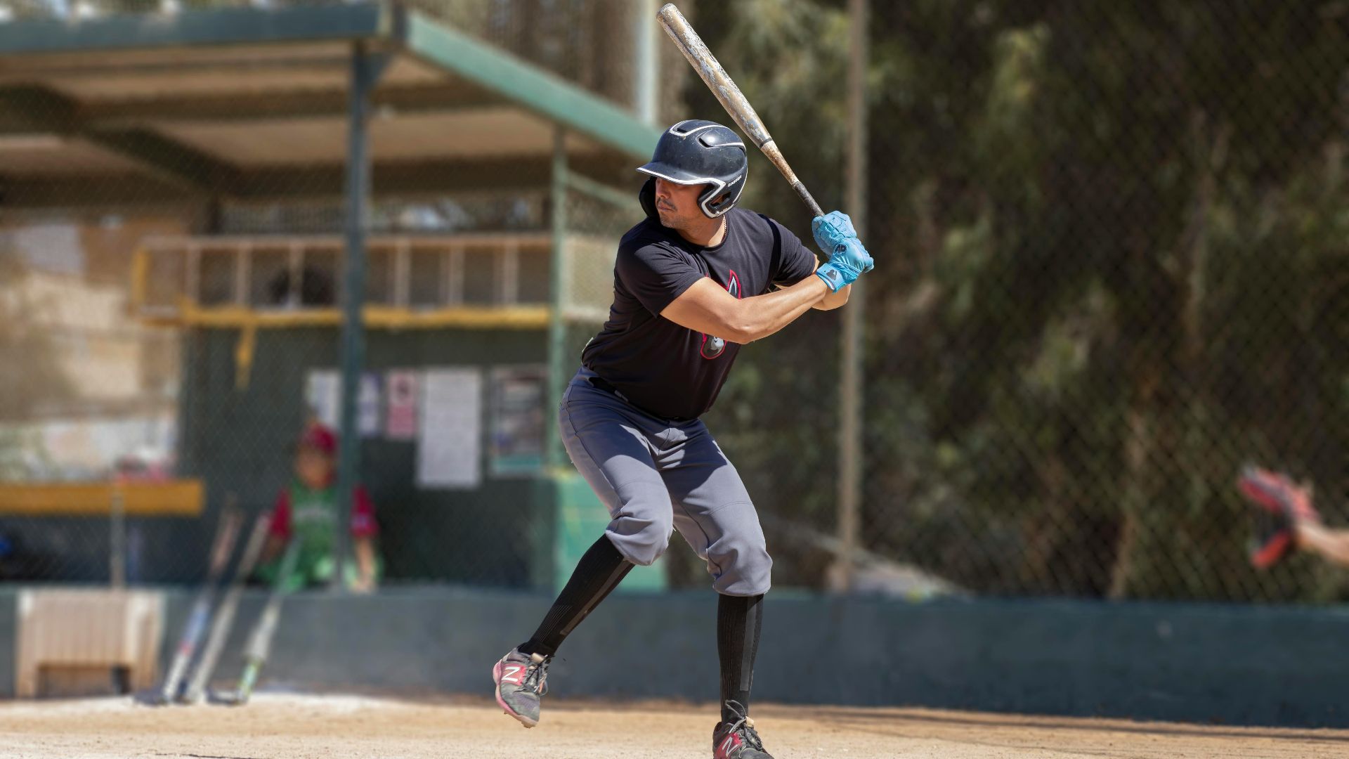 A baseball player in action at a sunlit outdoor baseball field, preparing to swing.
