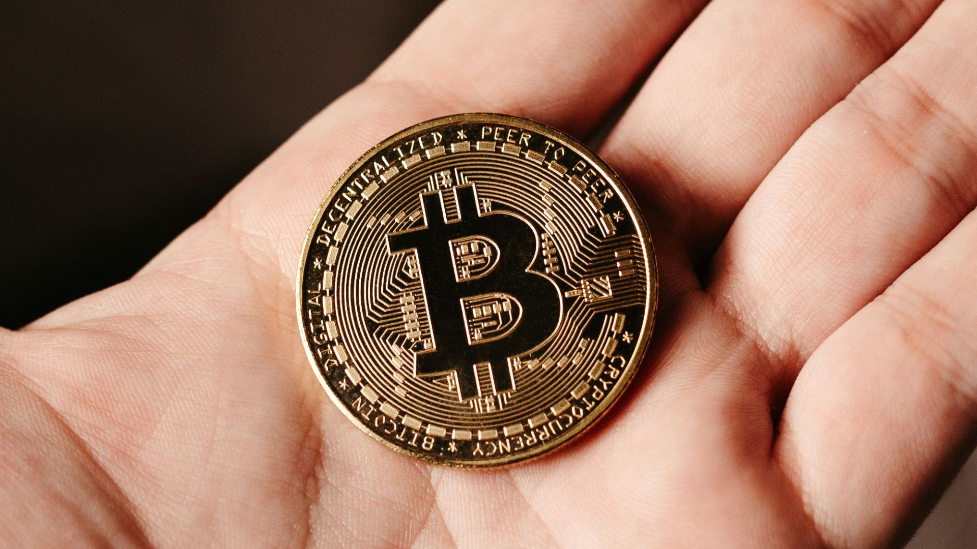 A detailed view of a Bitcoin coin resting in a human hand, symbolizing cryptocurrency.