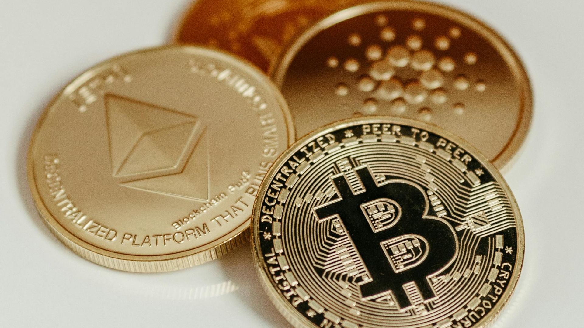 Elegant display of Bitcoin, Ethereum, and Cardano coins on a neutral background.
