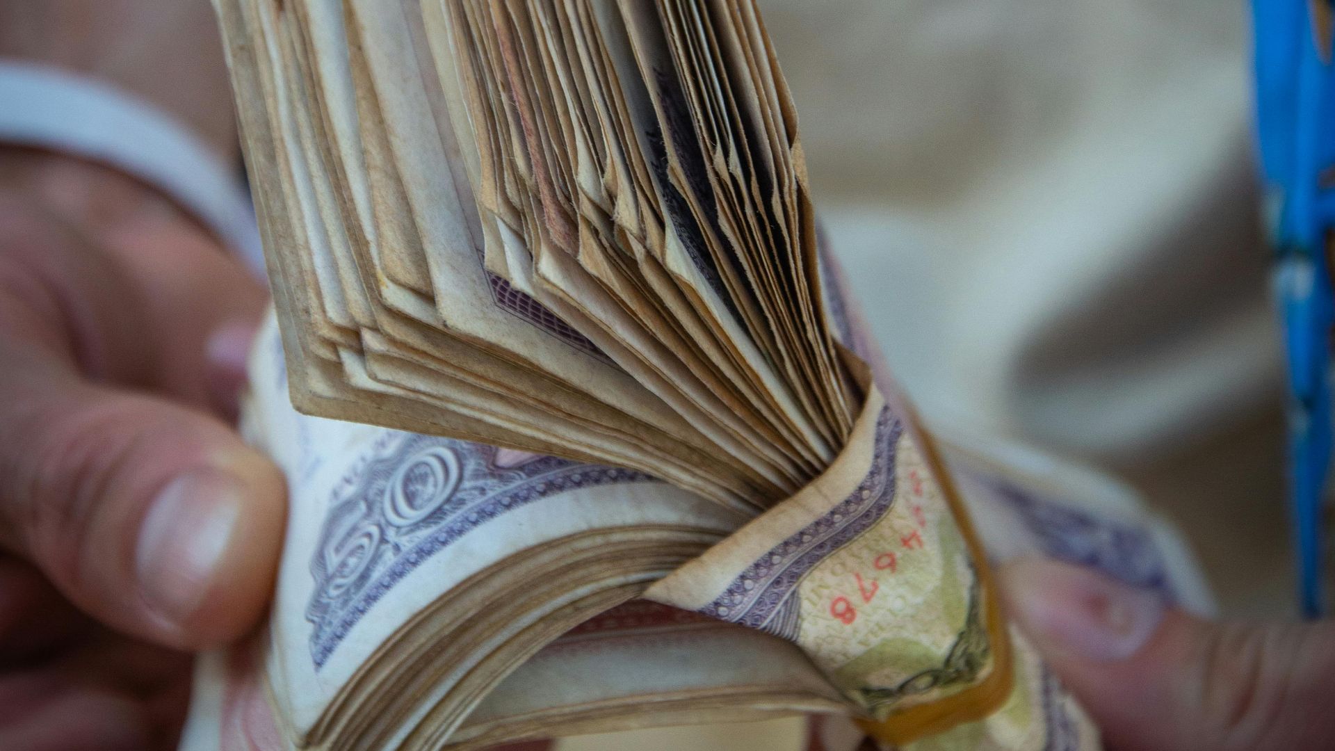 A person holding a large bundle of paper currency with both hands.
