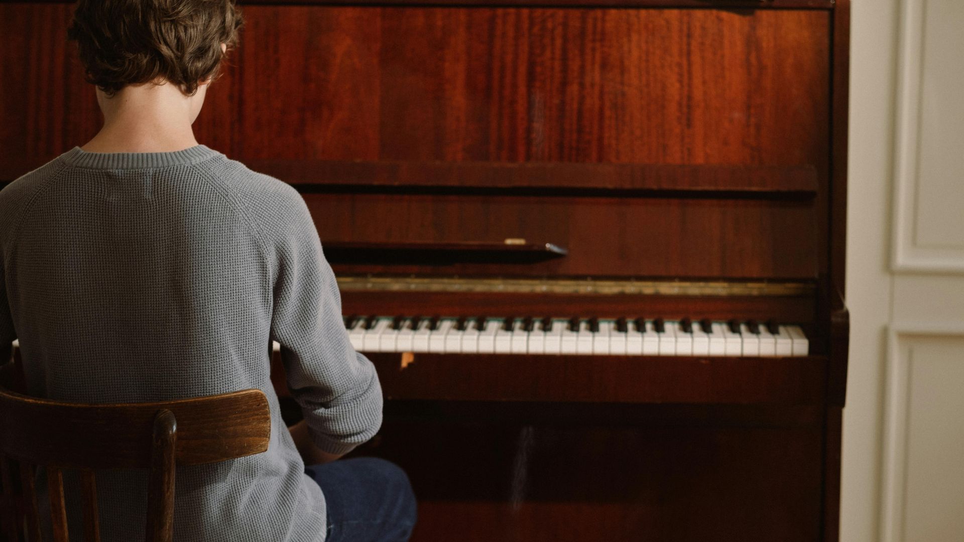 A person sitting and practicing piano indoors, creating a serene musical atmosphere.
