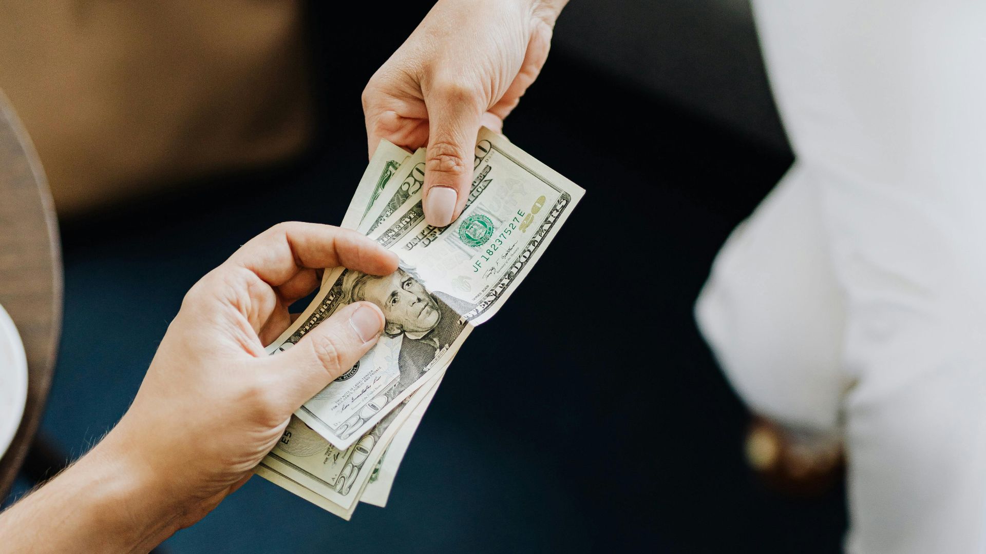Close-up of hands exchanging cash, representing a financial transaction or payment.