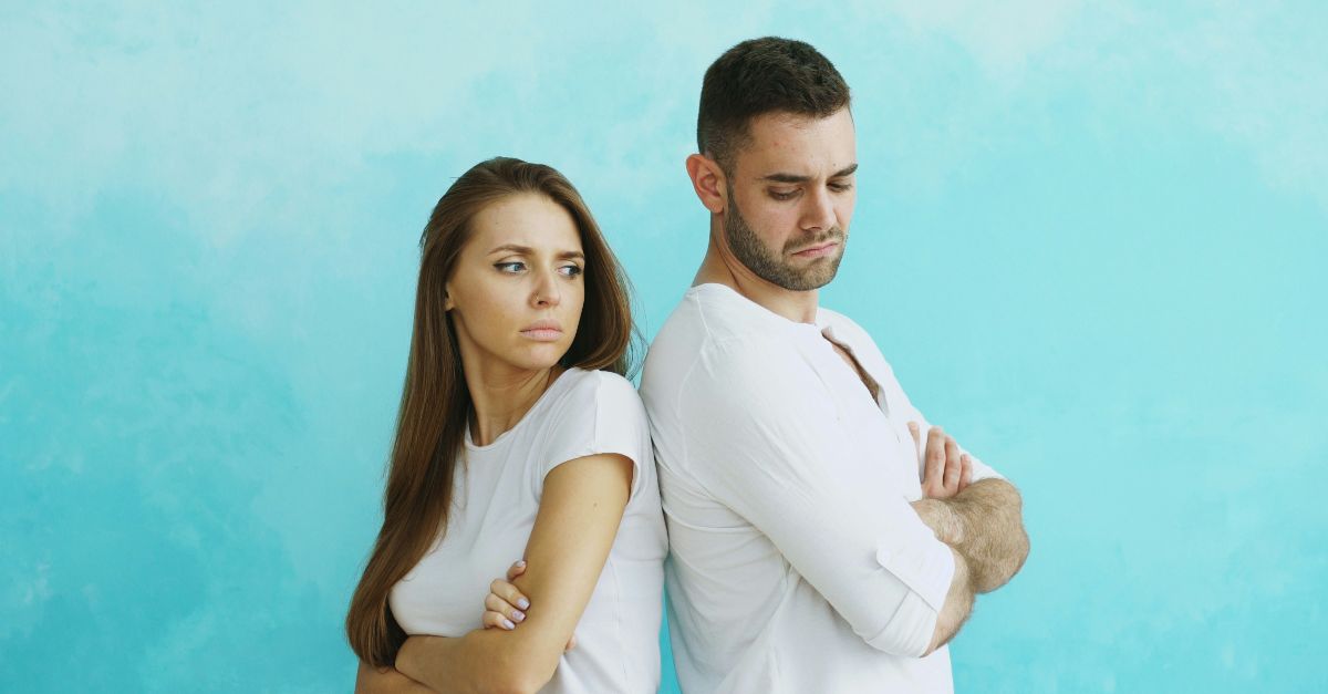 Couple standing back to back with arms crossed