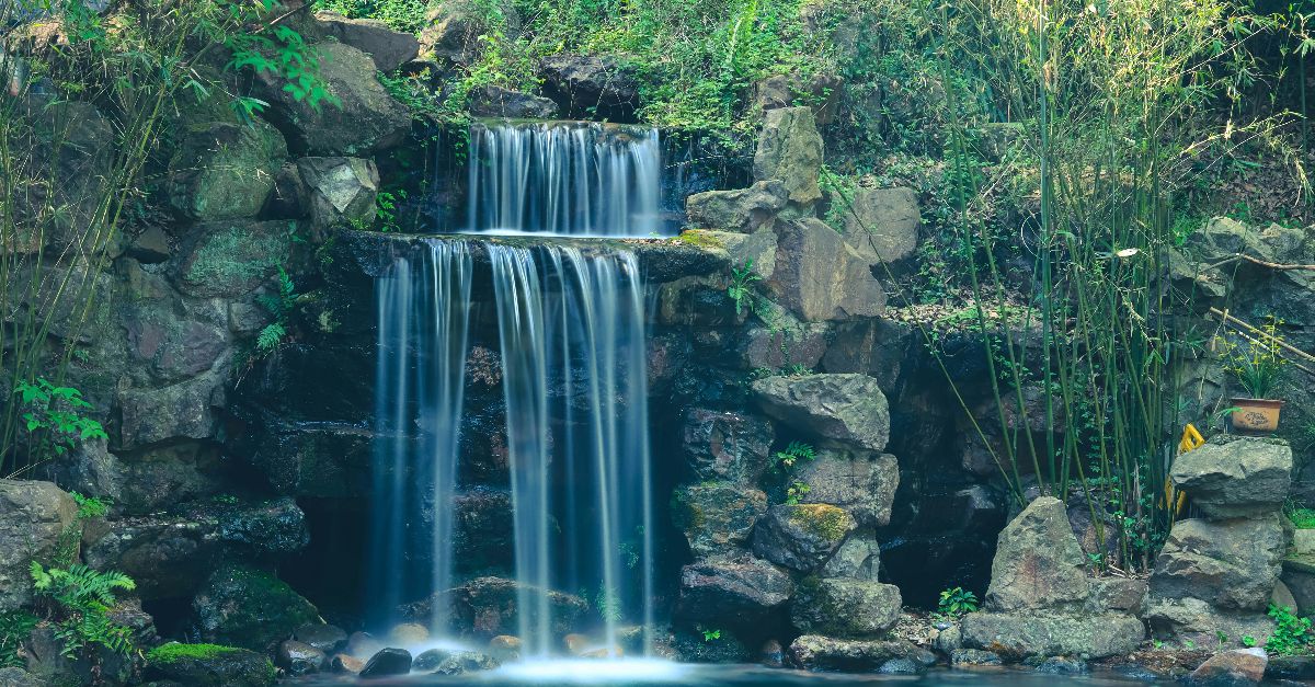 A tranquil waterfall cascading over rocks in a lush forest near Hangzhou, China.
