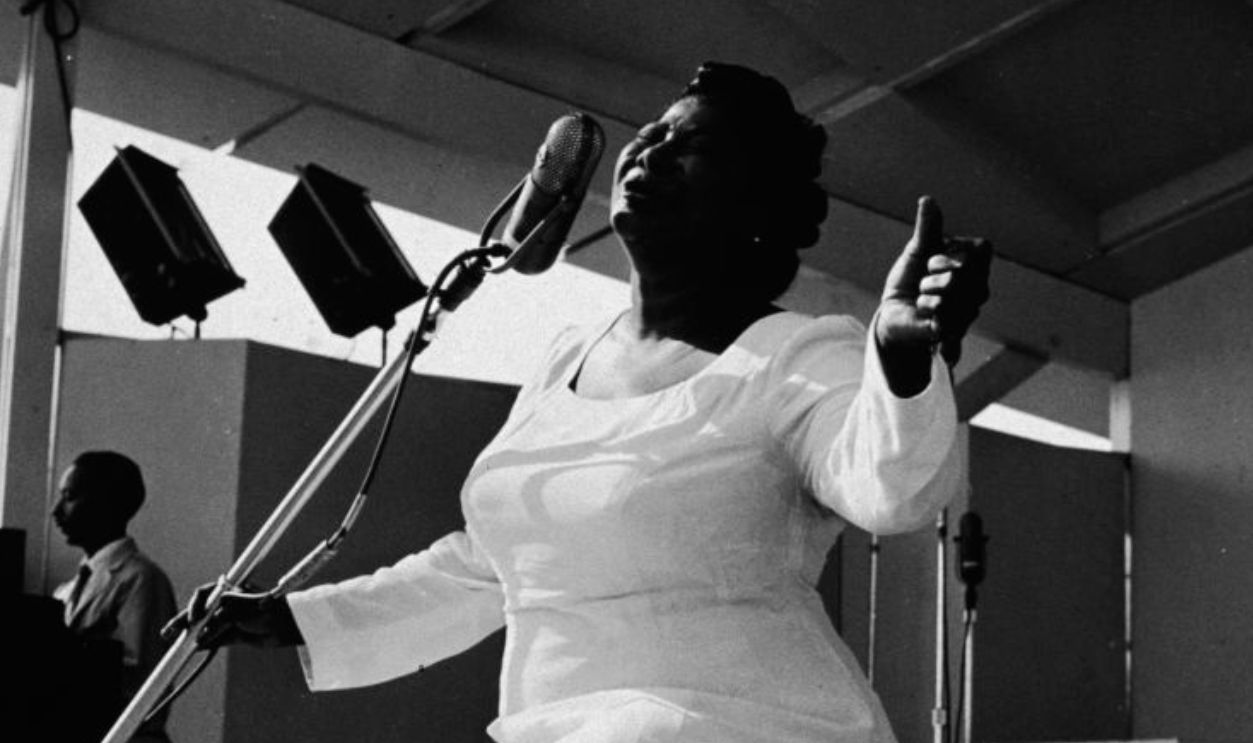 American gospel singer Mahalia Jackson (1911 - 1972) sings on bended knee with her arms outstretched at the Newport Jazz Festival, Newport, Rhode Island, July 7, 1957.