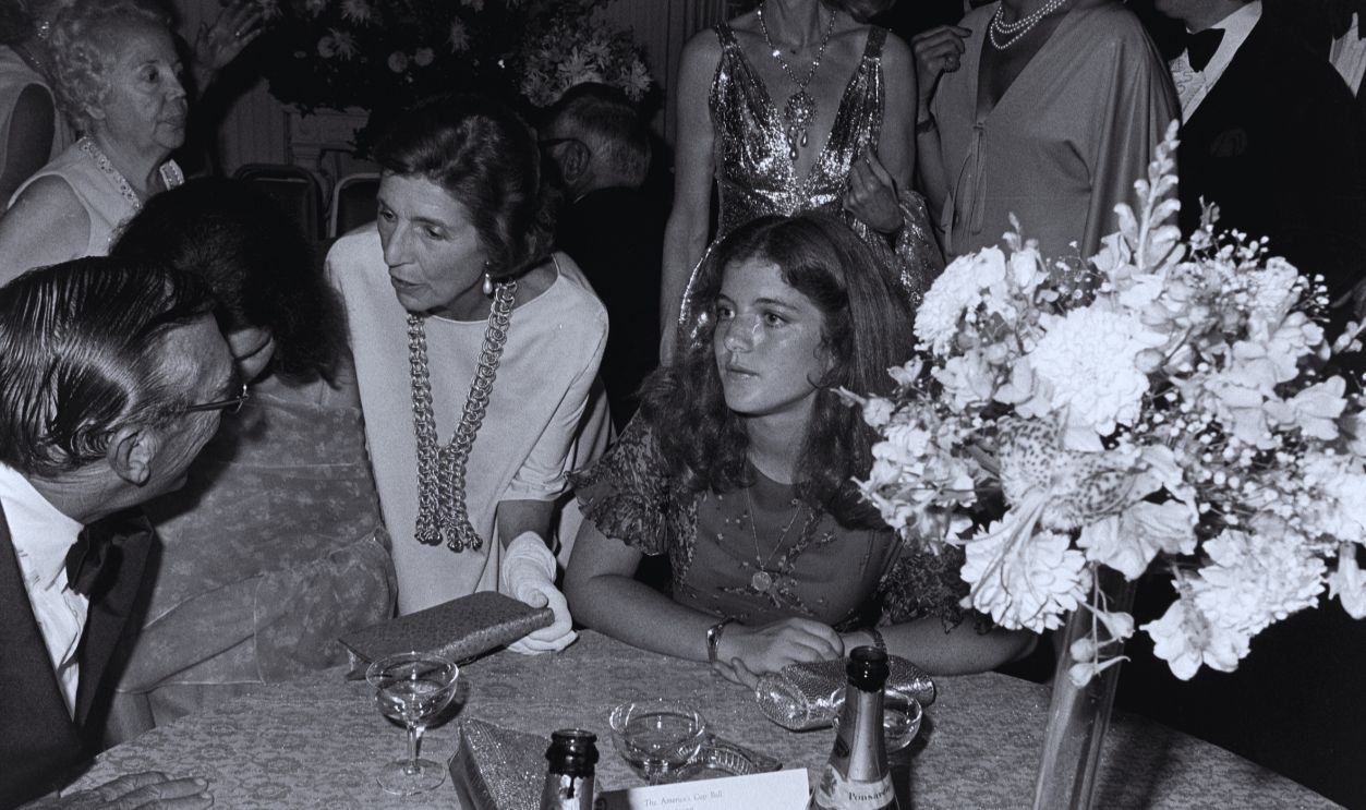 Gettyimages - 1762901977, America's Cup Ball (L-R, front row) Jack Fallon, Jacqueline Bouvier Kennedy Onassis (face obscured), Janet Auchincloss, and Caroline Kennedy attend a gala at Rosecliffe, a mansion in Newport, Rhode Island, on August 14, 1977.