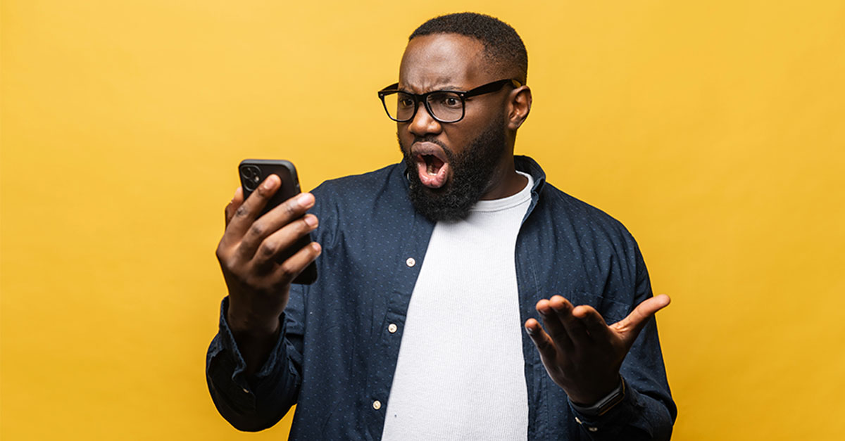 Shocked black man staring at phone
