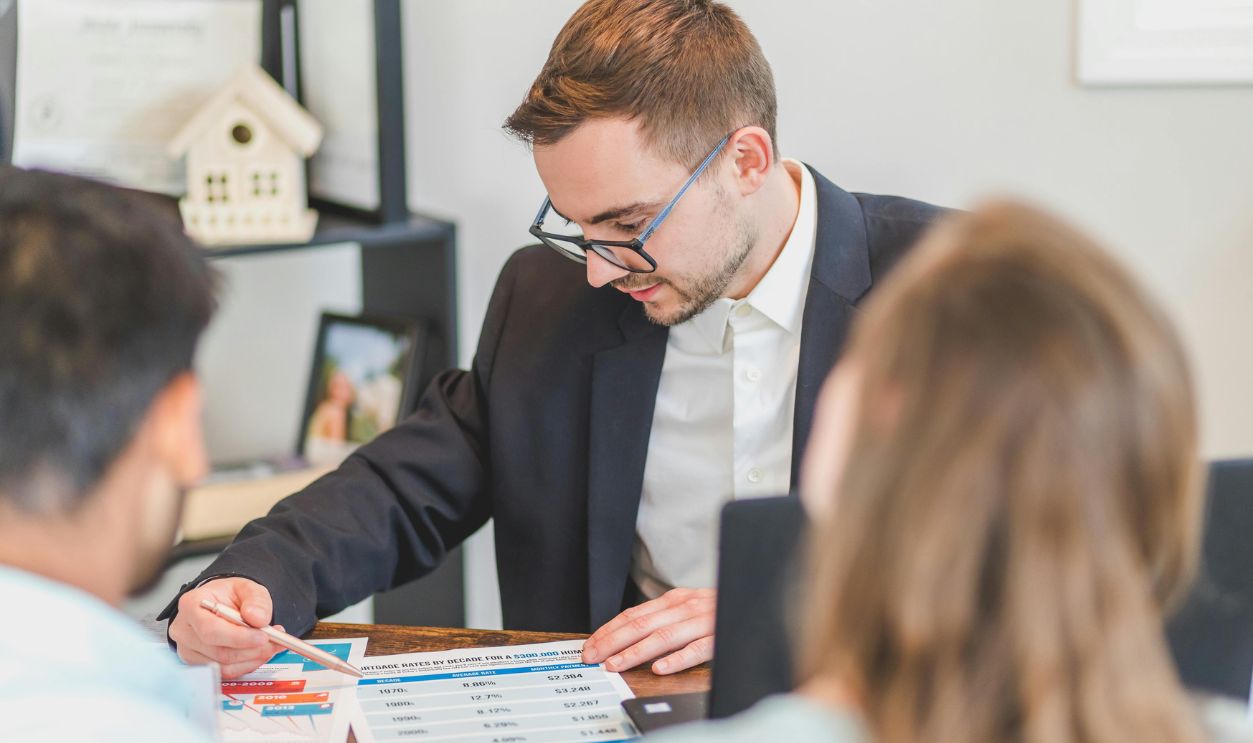 A real estate agent explains mortgage options to clients in an office setting.