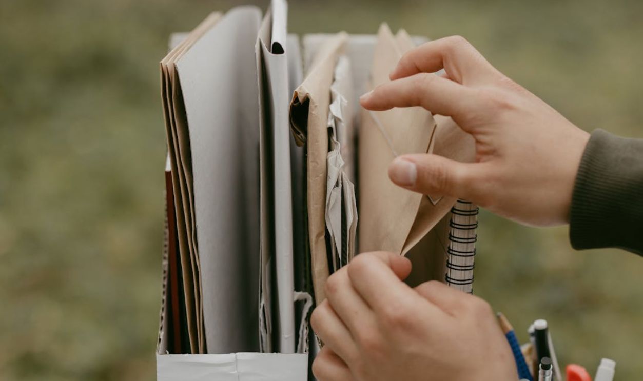Hands organizing documents and envelopes, emphasizing office work and organization outdoors