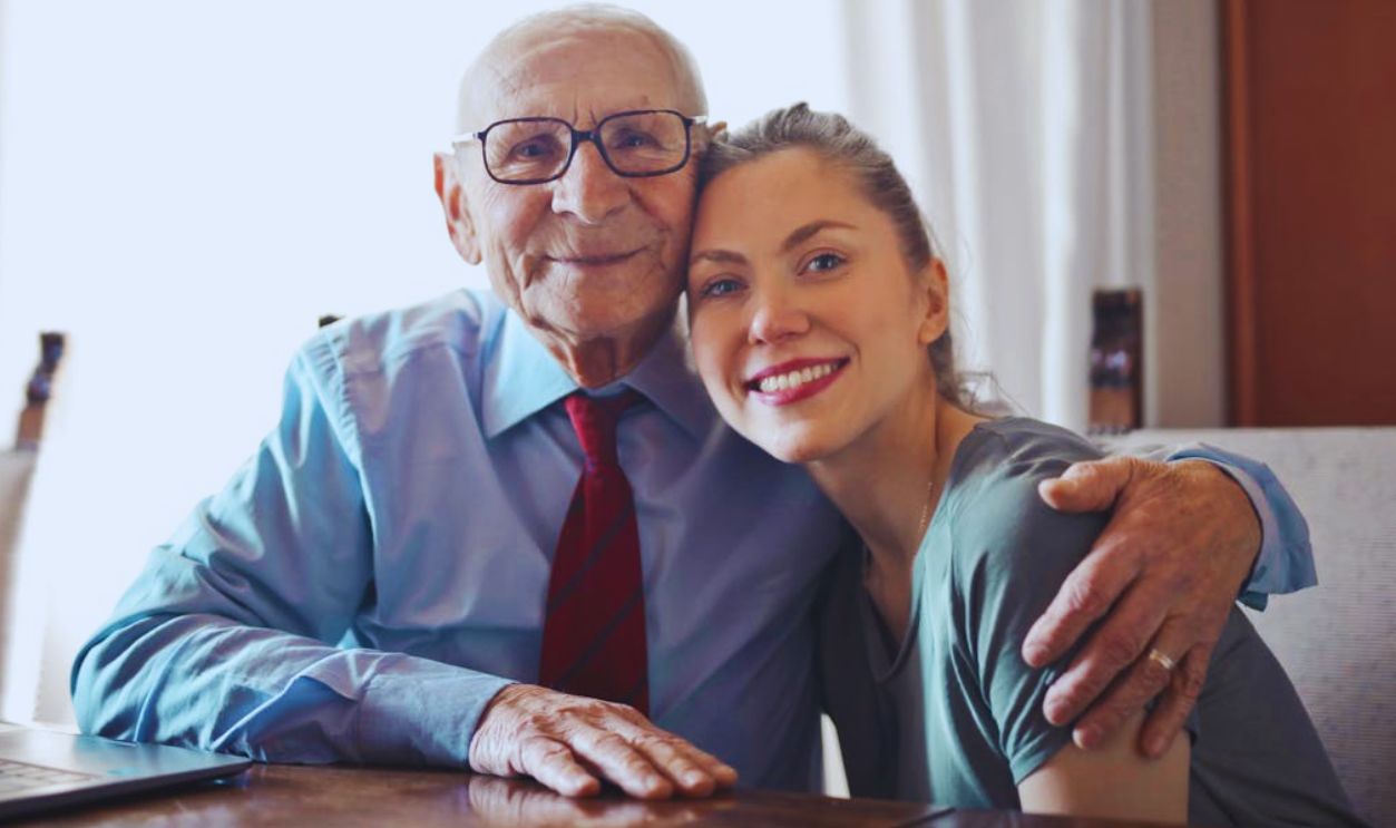 A joyful elderly man and young woman sharing an affectionate embrace indoors