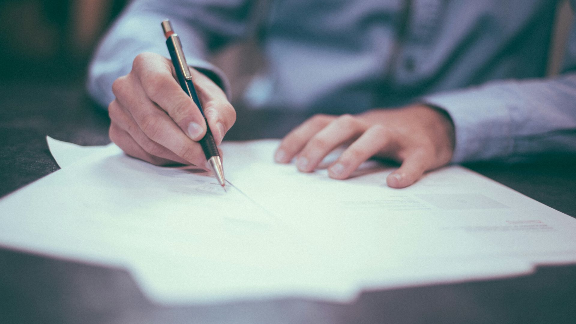 man writing on paper