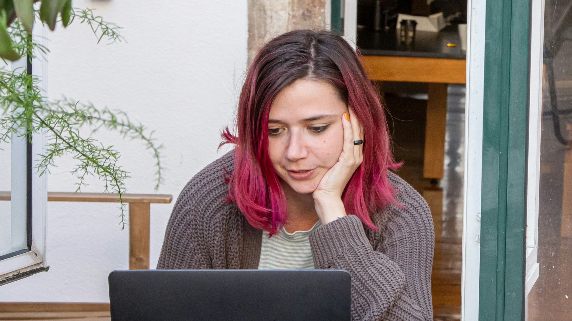 a woman with pink hair is looking at a laptop