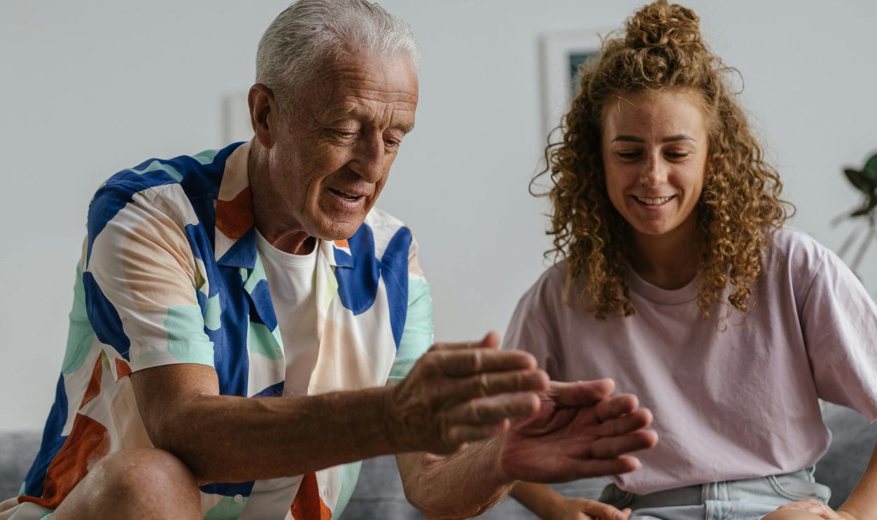 A senior man and young woman enjoying a dice game together on the couch
