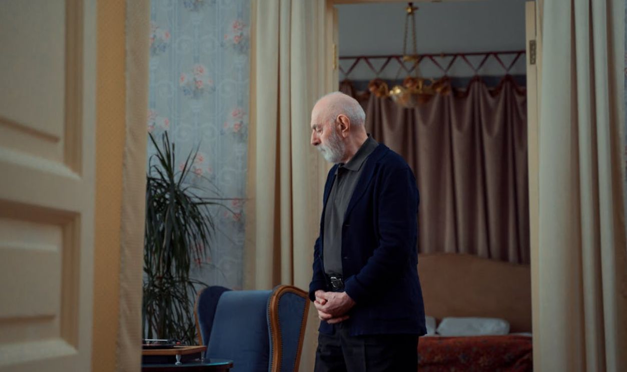 Elderly man standing thoughtfully in a vintage styled room with elegant decor