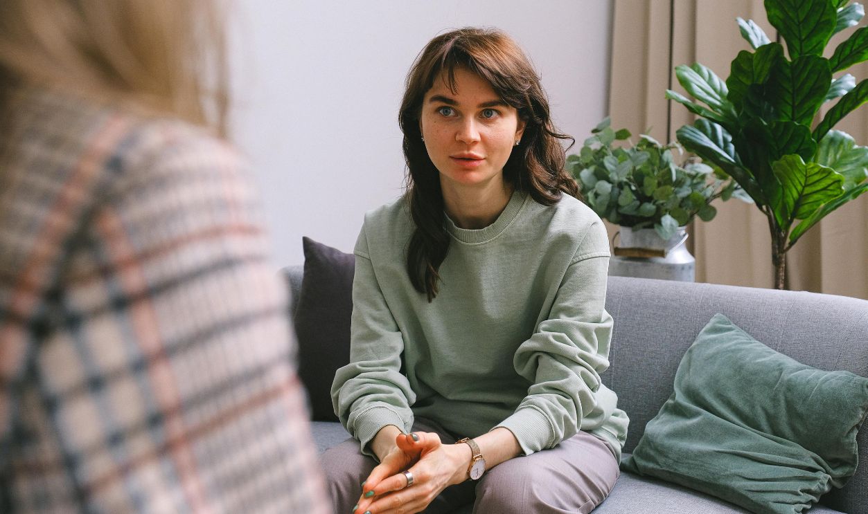 A focused woman during a therapy session, seated on a sofa indoors