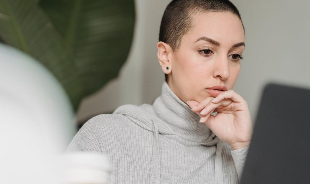 Woman with short hair concentrates deeply while working on a laptop indoors, emphasizing focus and modern work environment