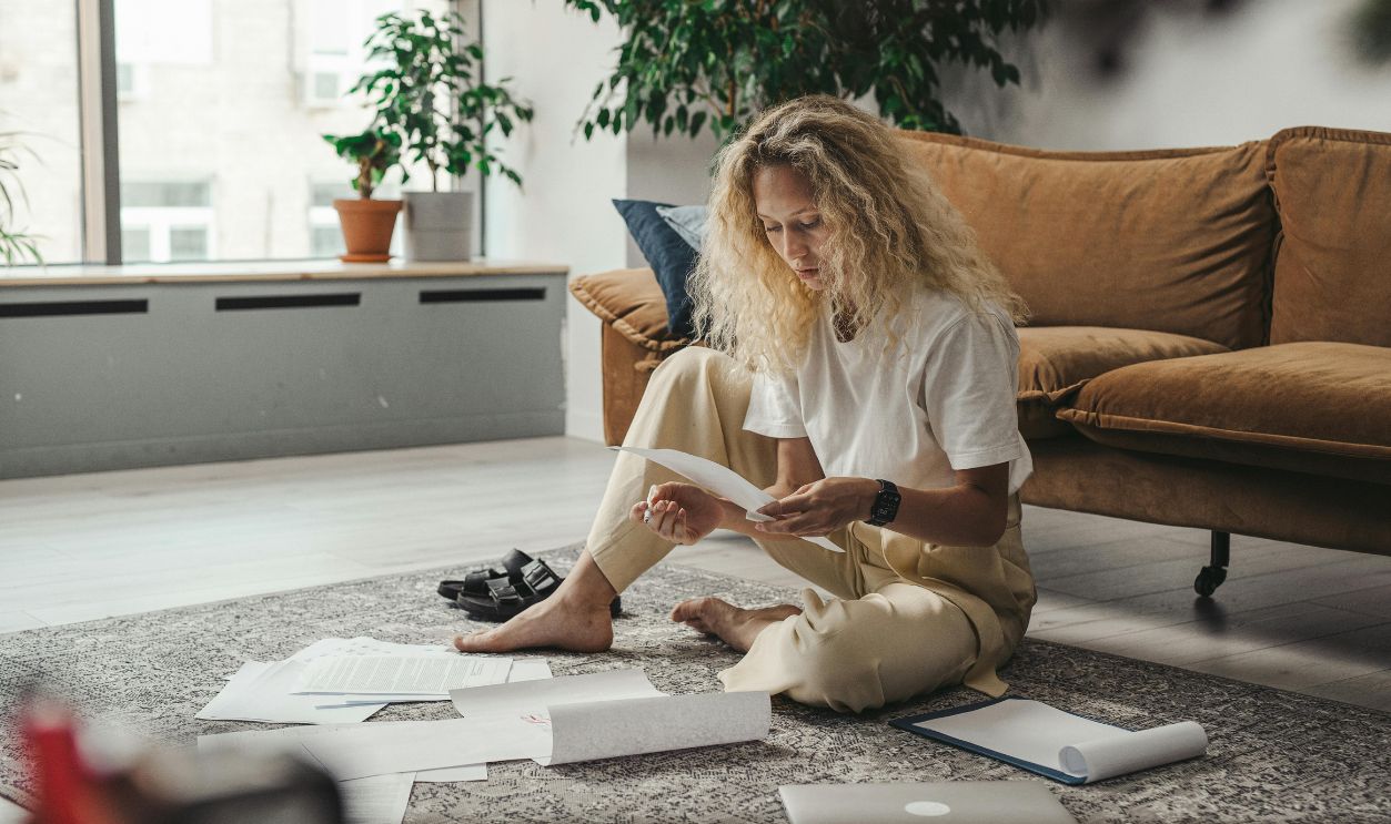 Woman sitting on the floor at home, reviewing paperwork in a relaxed environment