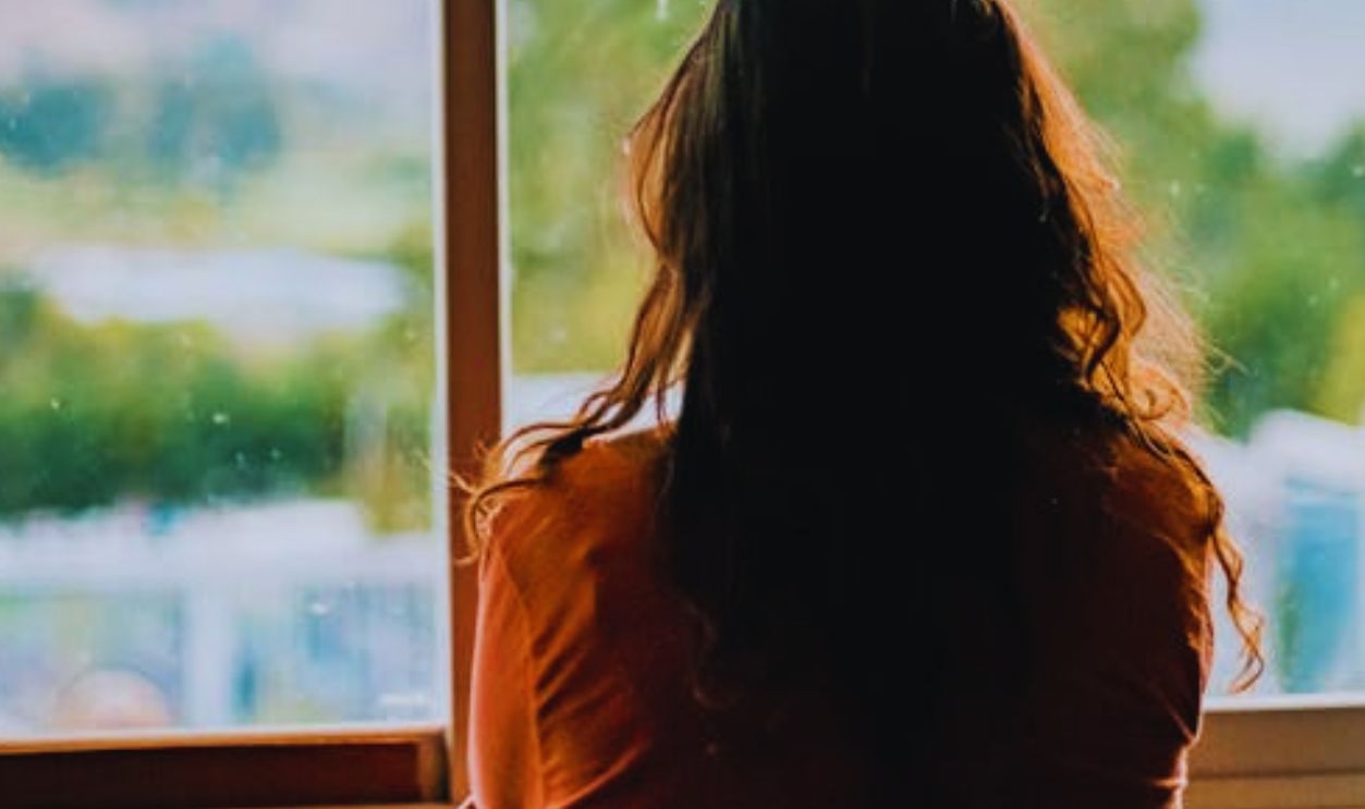 Silhouette of a woman looking out a window at a scenic mountain view in Cajamarca, Peru.