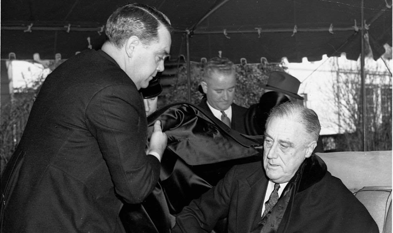 President Franklin Delano Roosevelt prepares to leave the White House for services at St. John's Episcopal Church, the first item on the Inaugural Day program. President Roosevelt is assisted with his cape by Tom Qualters, the President's bodyguard.