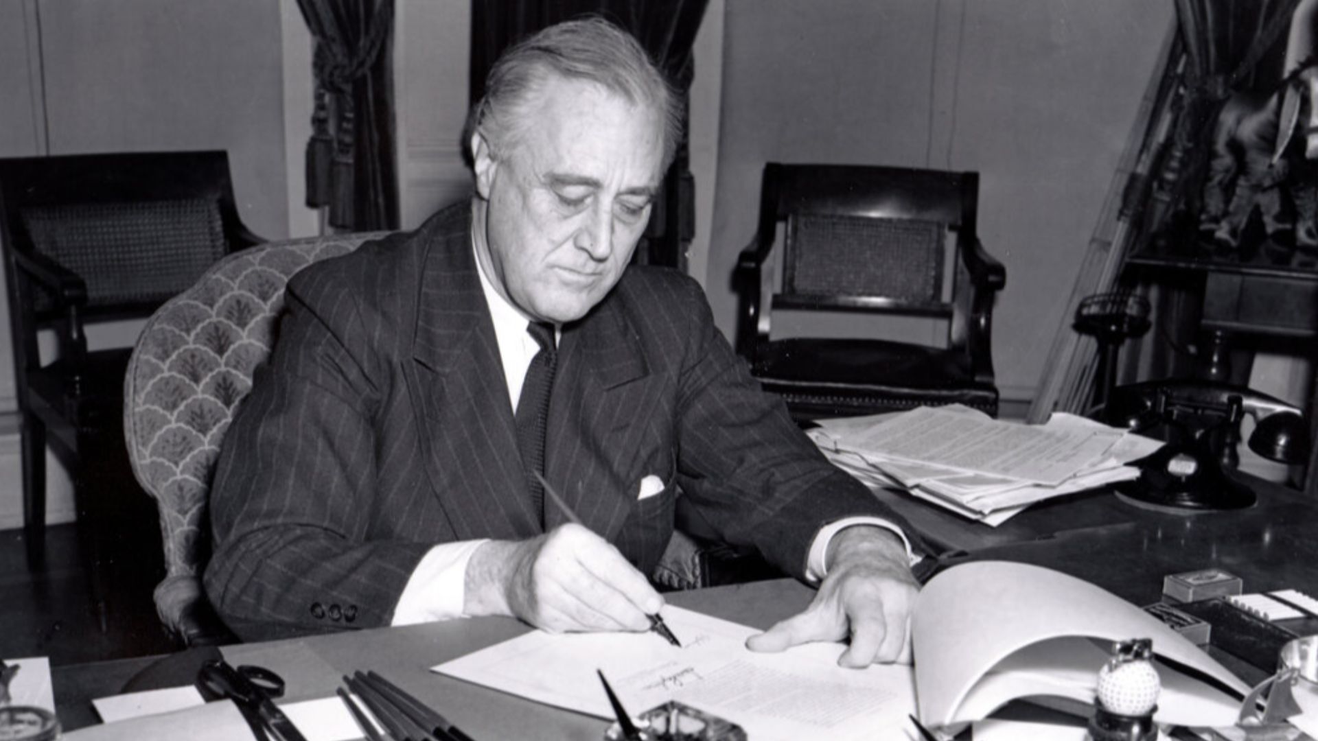 President Franklin D. Roosevelt, half-length portrait, seated at desk, looking down, signing H.R. 1776, the lend-lease bill to give aid to Great Britain, China and Greece.