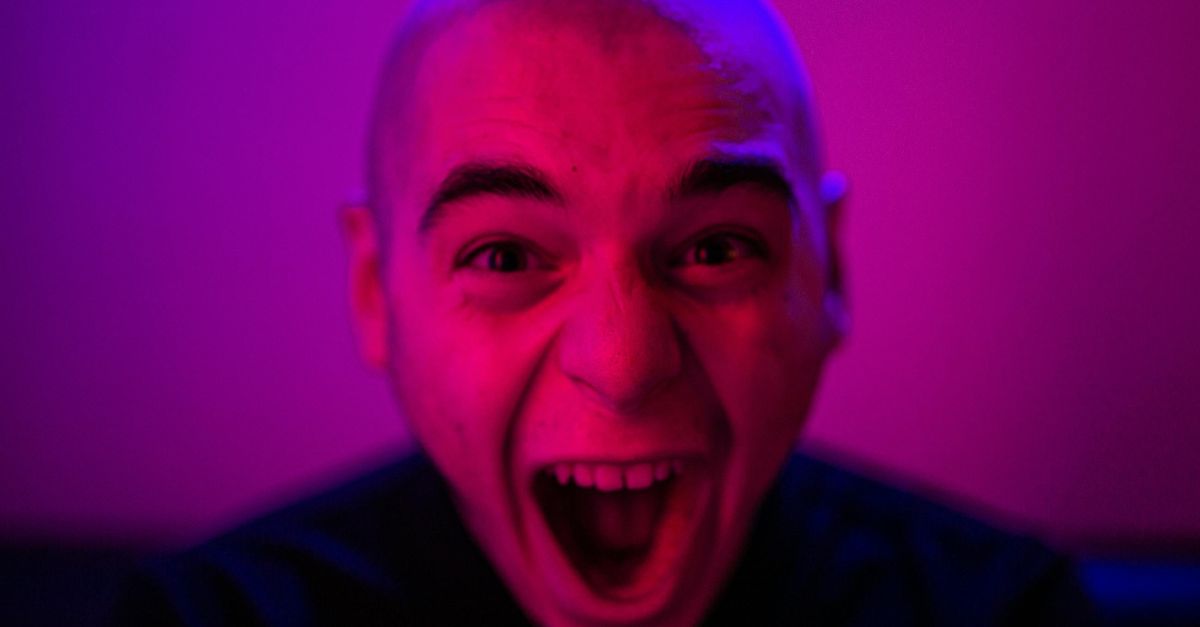 Dynamic close-up of a man with neon lighting, showcasing raw emotion and intensity.