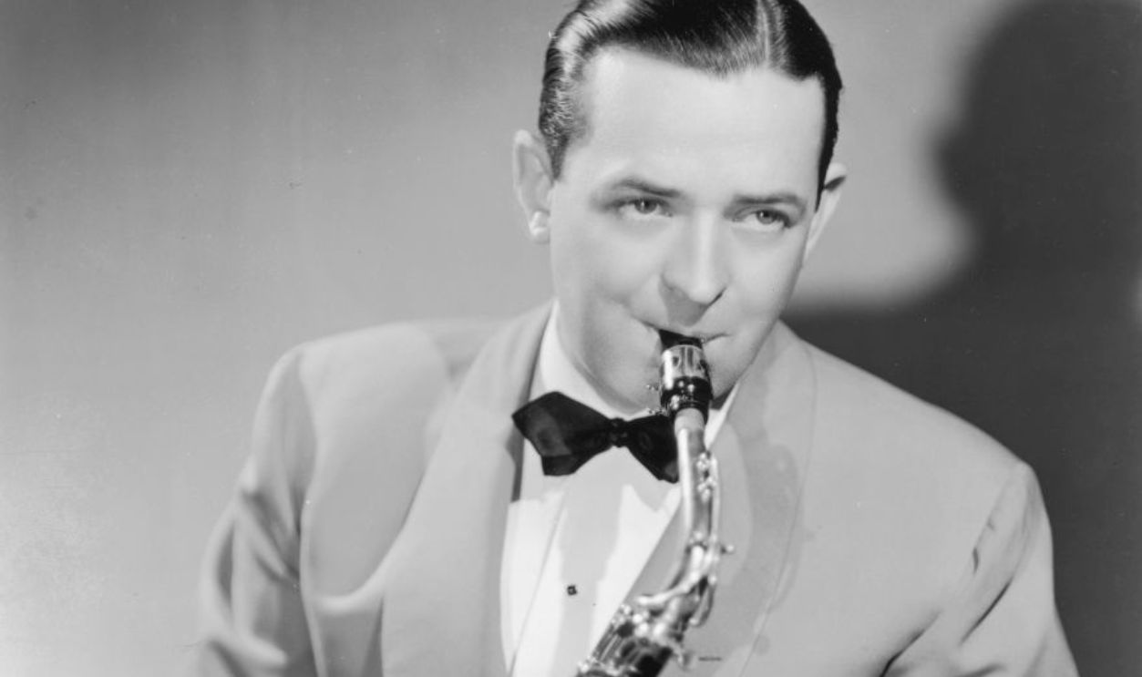 circa 1935: Studio portrait of American jazz saxophonist and bandleader Jimmy Dorsey playing a saxophone. Dorsey wears a light-colored blazer with a dark bow tie and dark pants. (