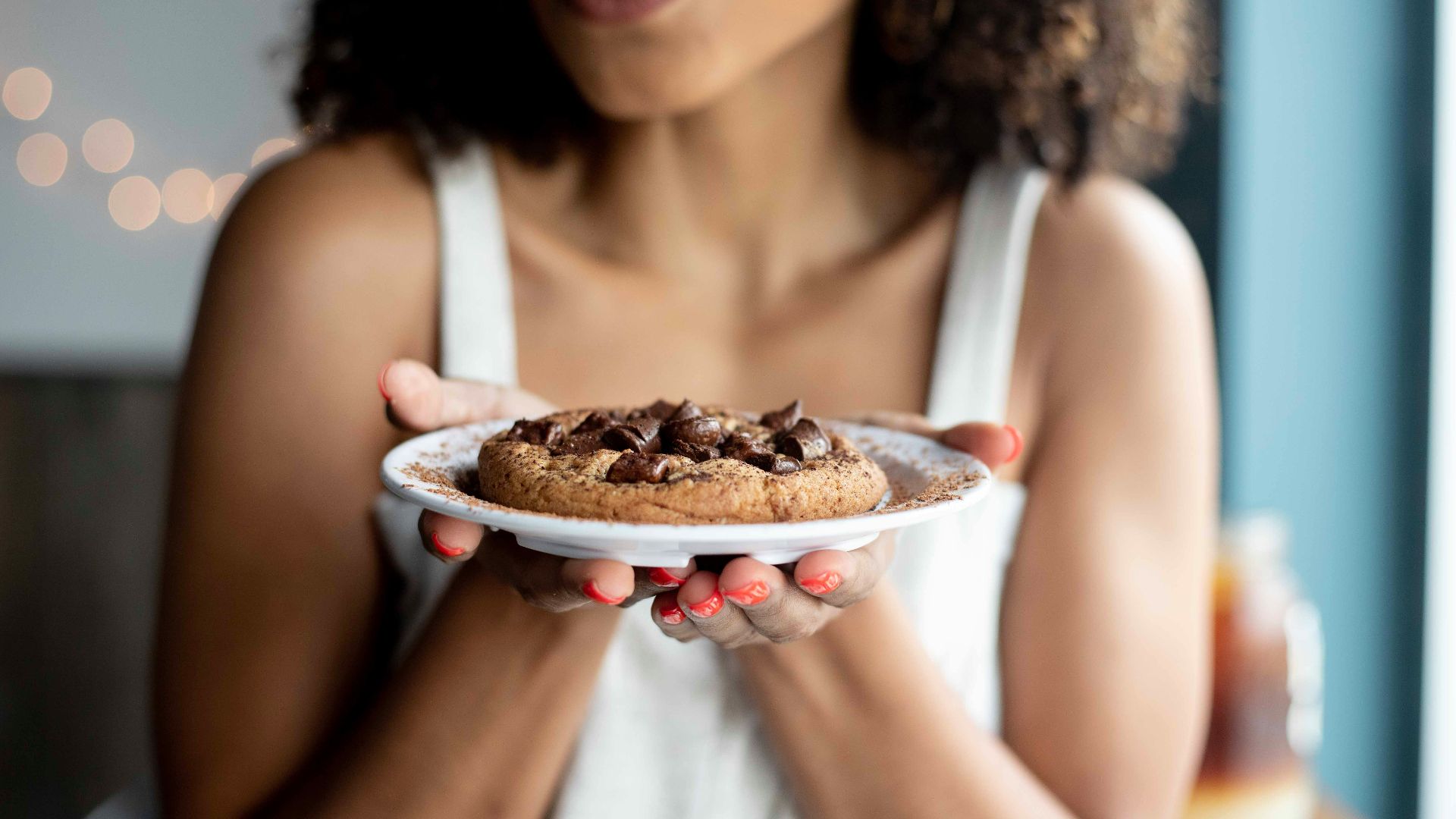woman holding white ceramic plate with cookies