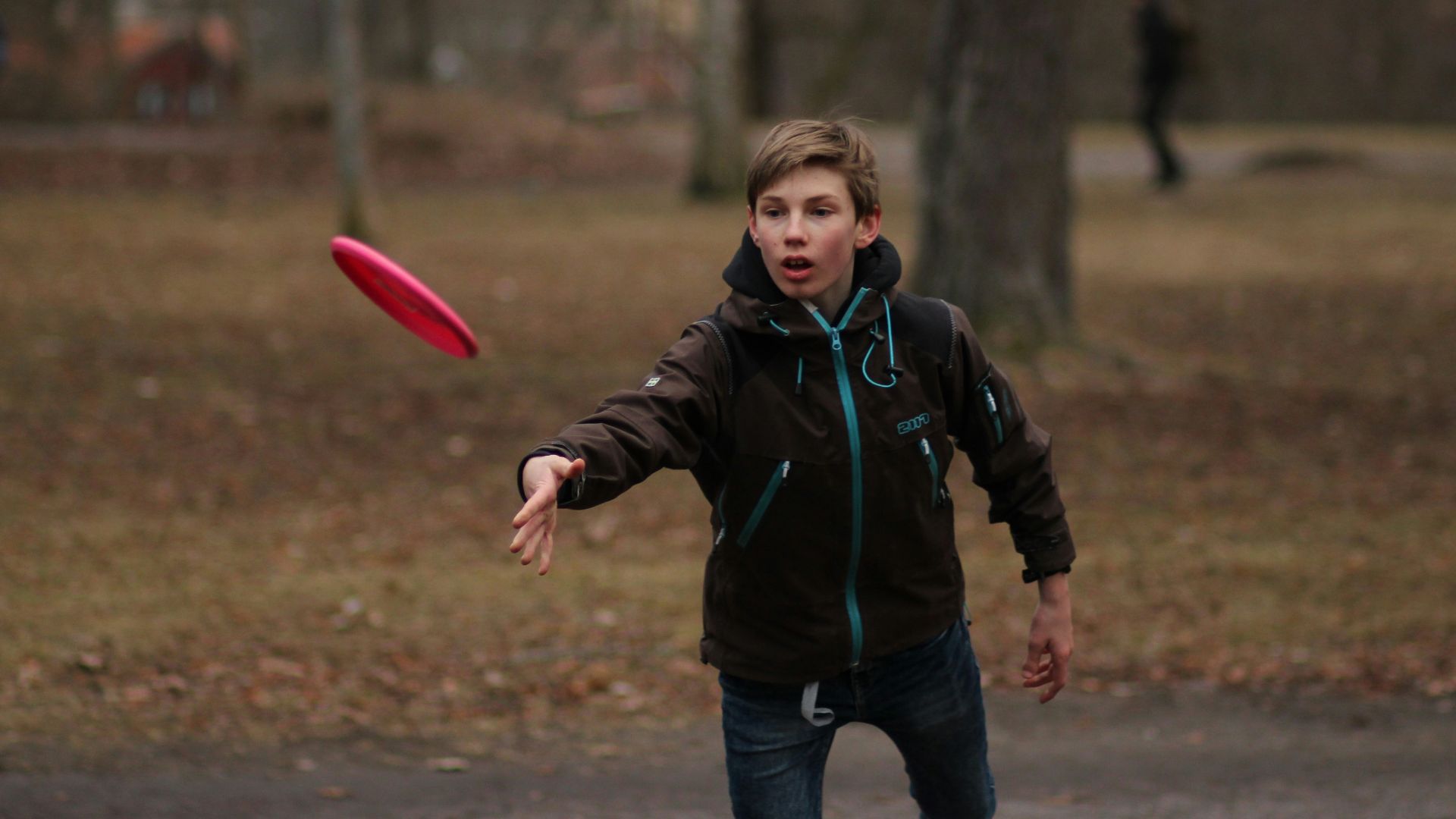 boy in green jacket holding pink balloon