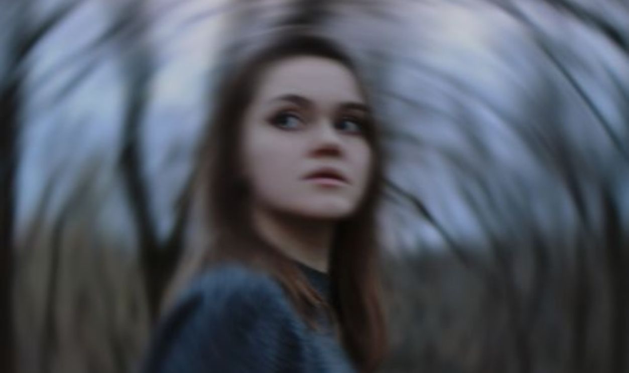Artistic photo of a young woman with motion blur effect in a forest setting.
