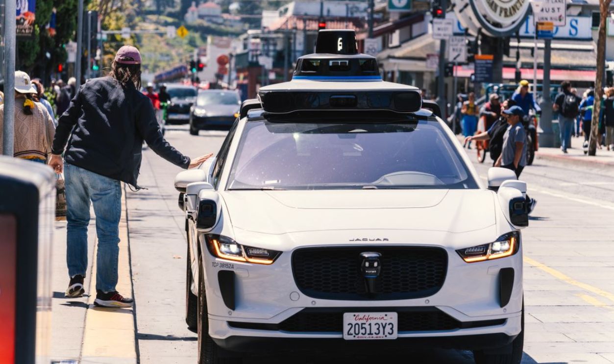 A self-driving car navigates through a bustling city street in San Francisco, capturing urban mobility in action.