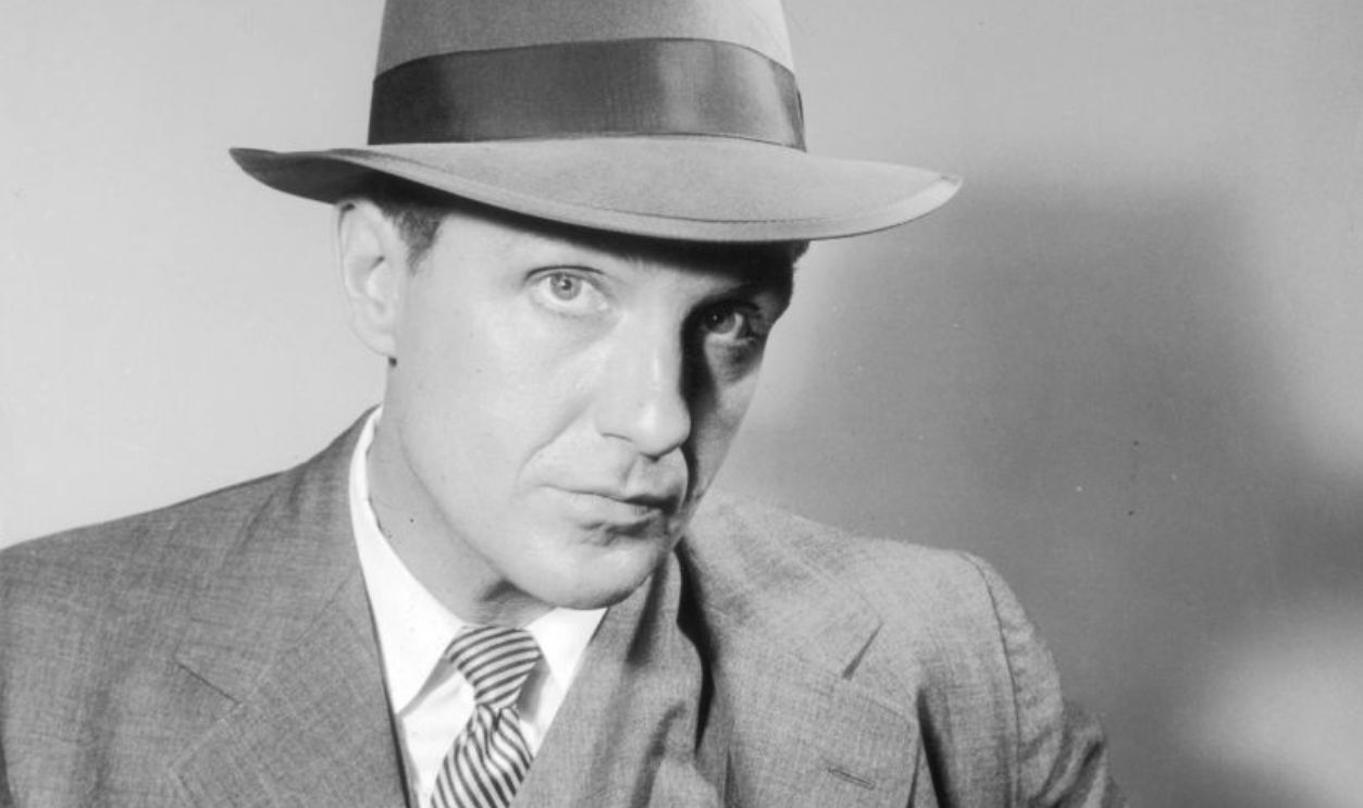 1959: American actor Robert Stack (1919 - 2003), in costume as Eliot Ness, holds a gun tucked in a shoulder holster in a promotional portrait for the television series, 'The Untouchables'.