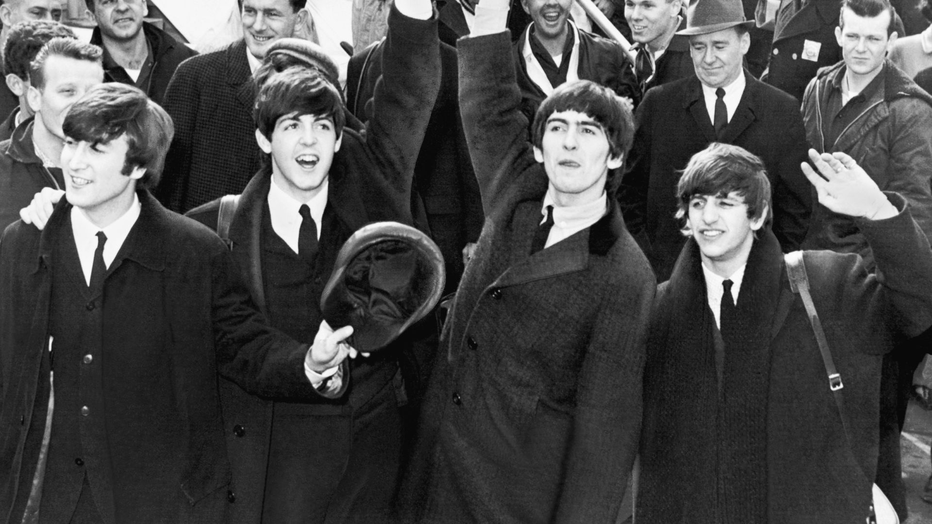 English band The Beatles wave to fans after arriving at Kennedy Airport.