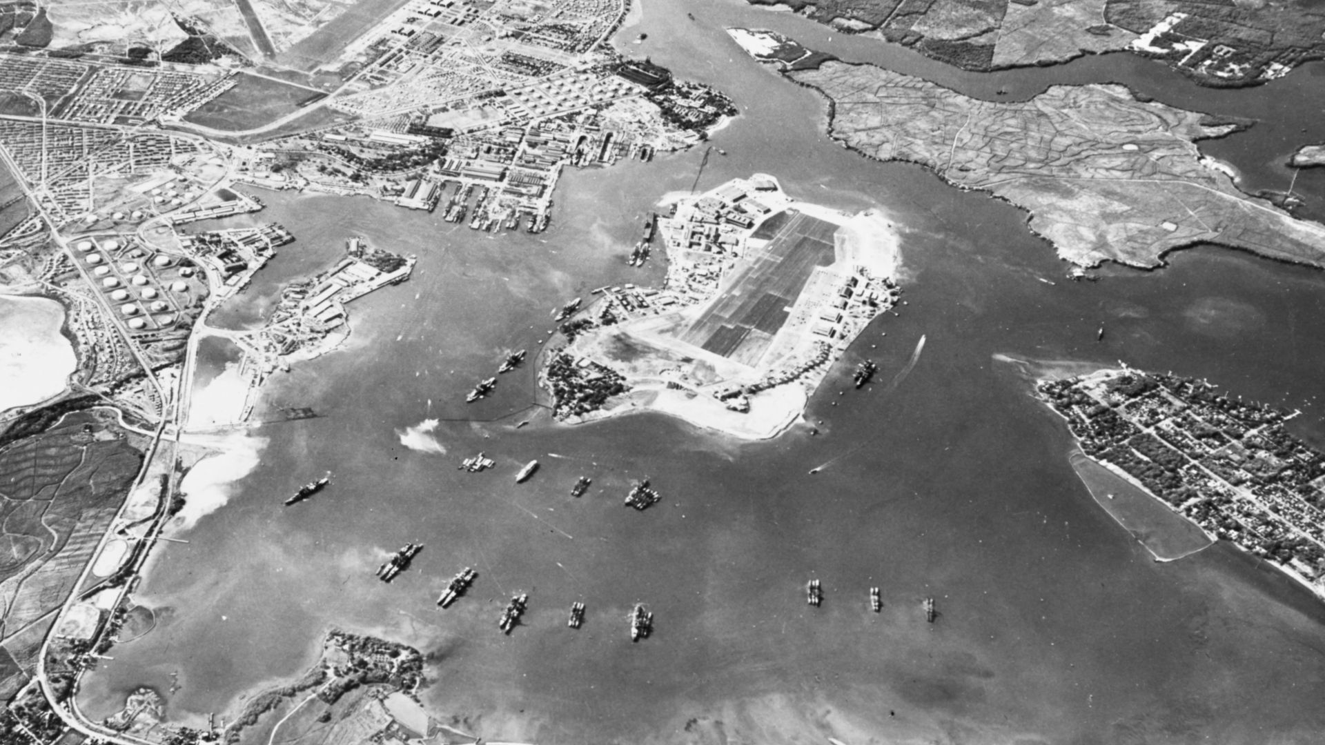 Aerial view of the U.S. Naval Operating Base, Pearl Harbor, Oahu, Hawaii (USA), looking southwest on 30 October 1941. Ford Island Naval Air Station is in the center, with the Pearl Harbor Navy Yard just beyond it, across the channel. The airfield in the u
