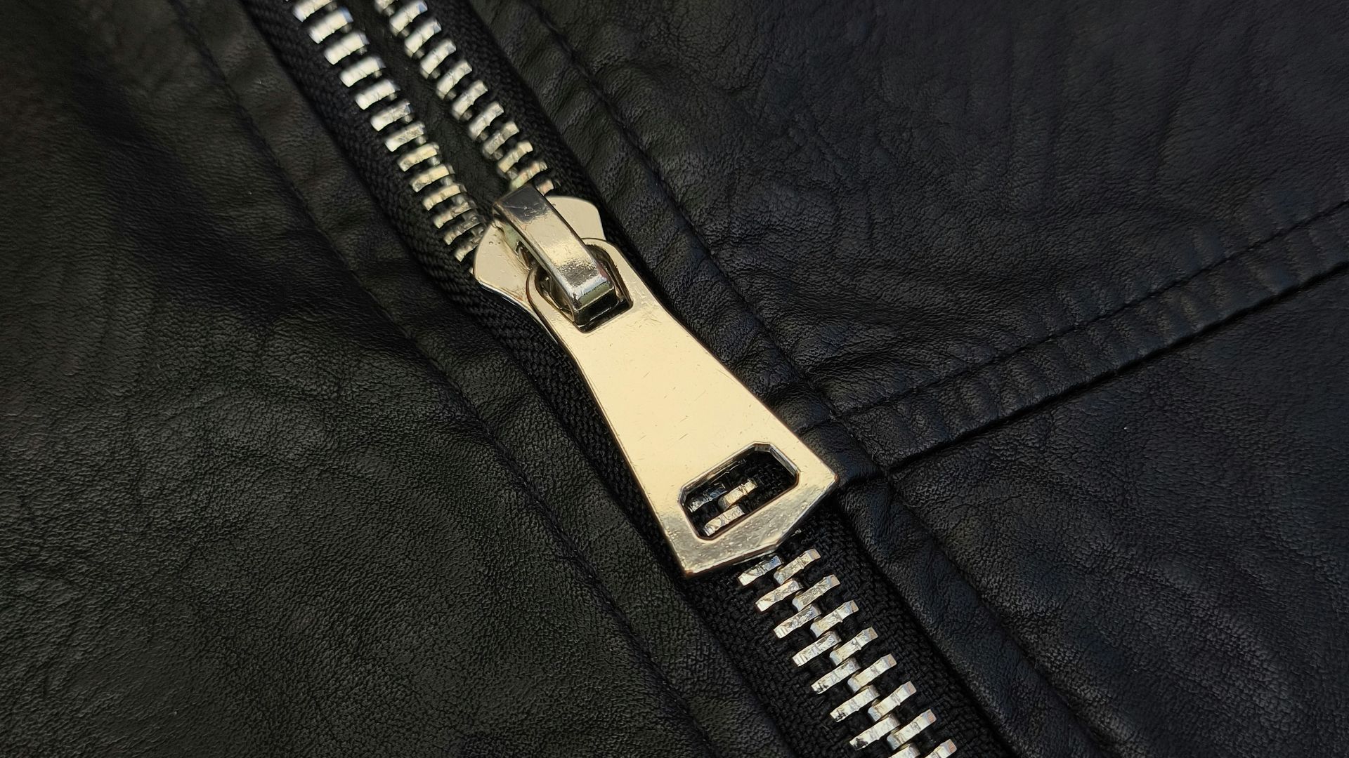 A close up of a zipper on a black leather jacket