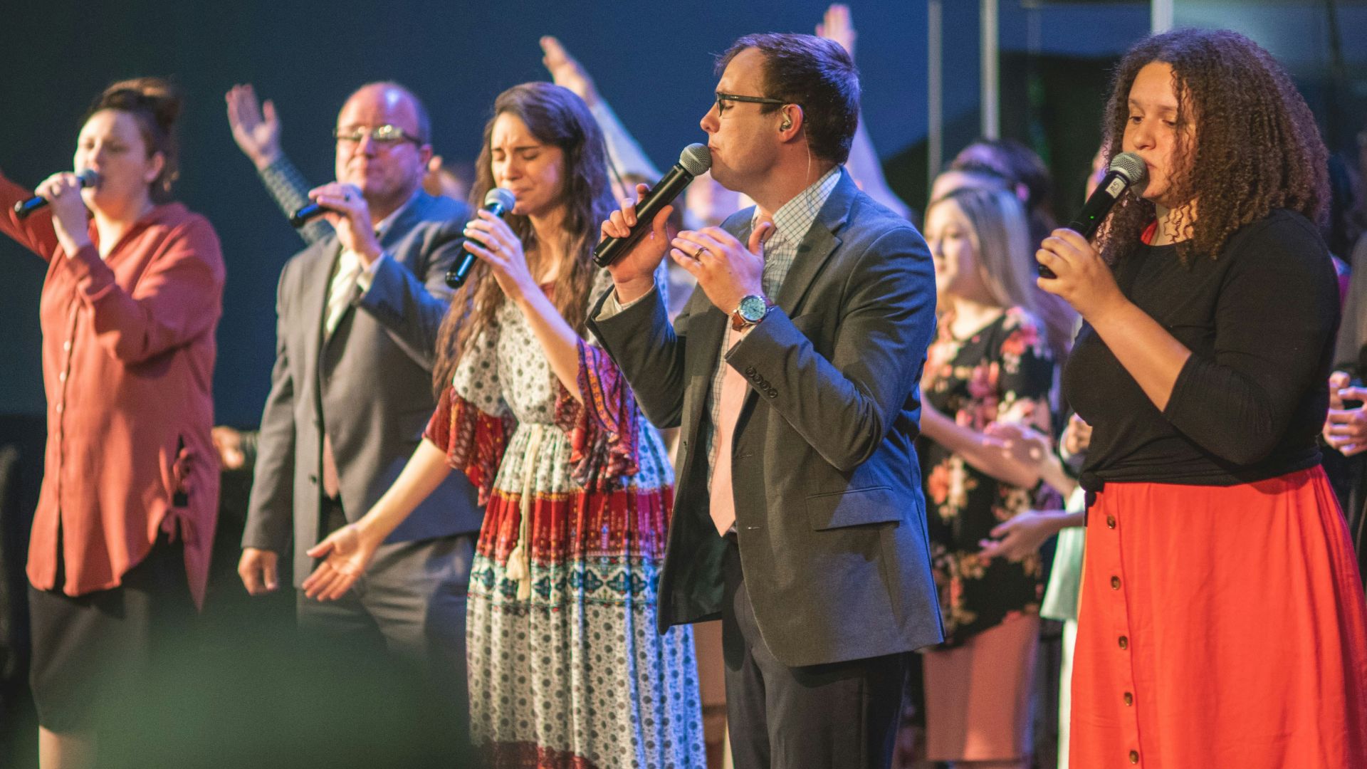 man in brown suit jacket holding microphone