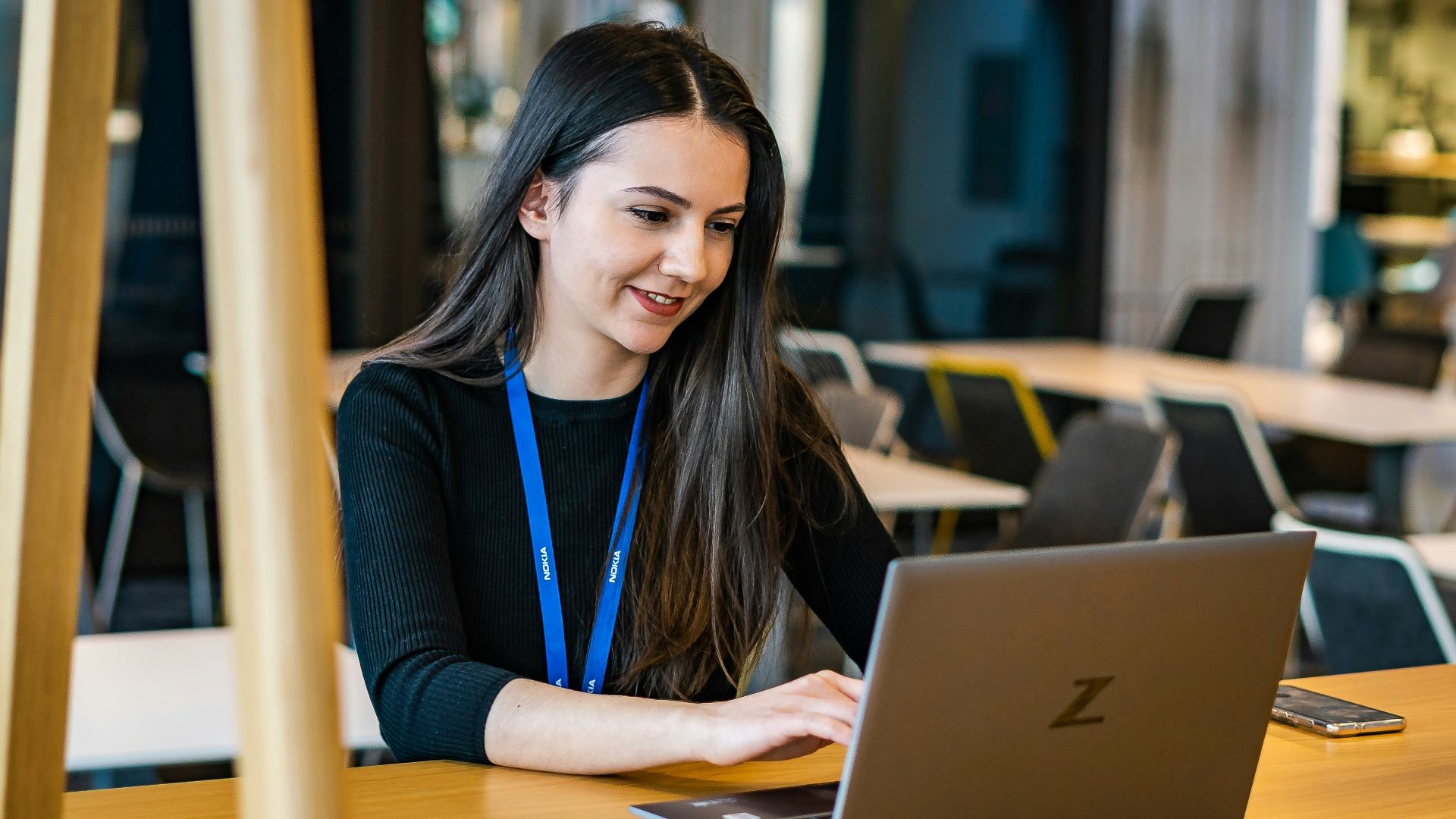 a woman sitting at a table using a laptop computer