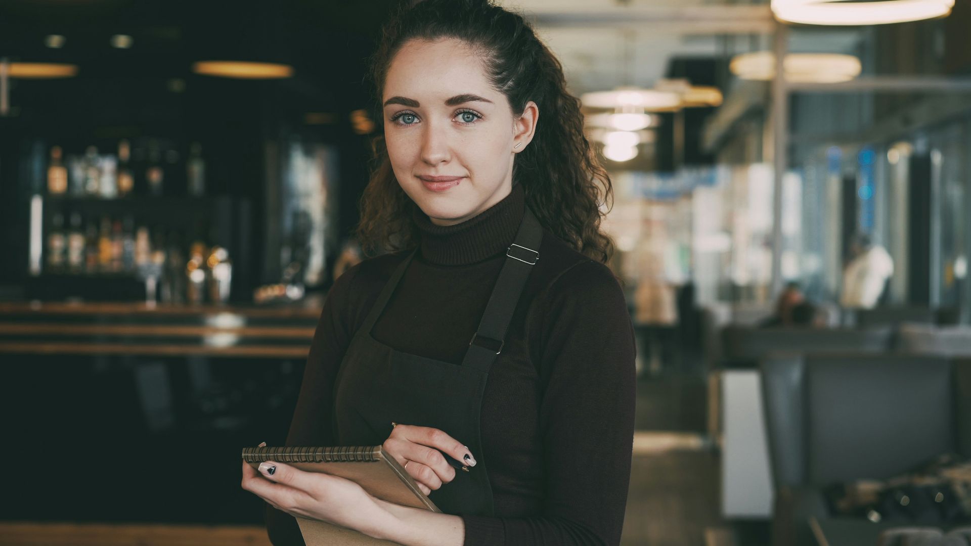 Woman in apron holding tablet in restaurant