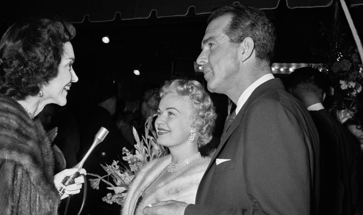 American journalist and actress Shirley Thomas (1920-2005) interviewing American actress, singer and dancer June Haver (1926-2005) and her husband, American actor Fred MacMurray (1908-1991) outside the premiere of 'Prince Valiant', held at Romanoff's in Los Angeles, California, 3rd April 1954.  