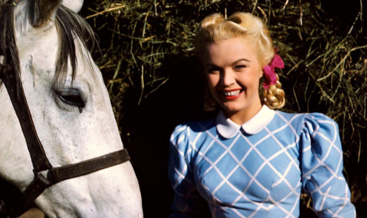 American actress June Haver in period costume with a horse, circa 1944.