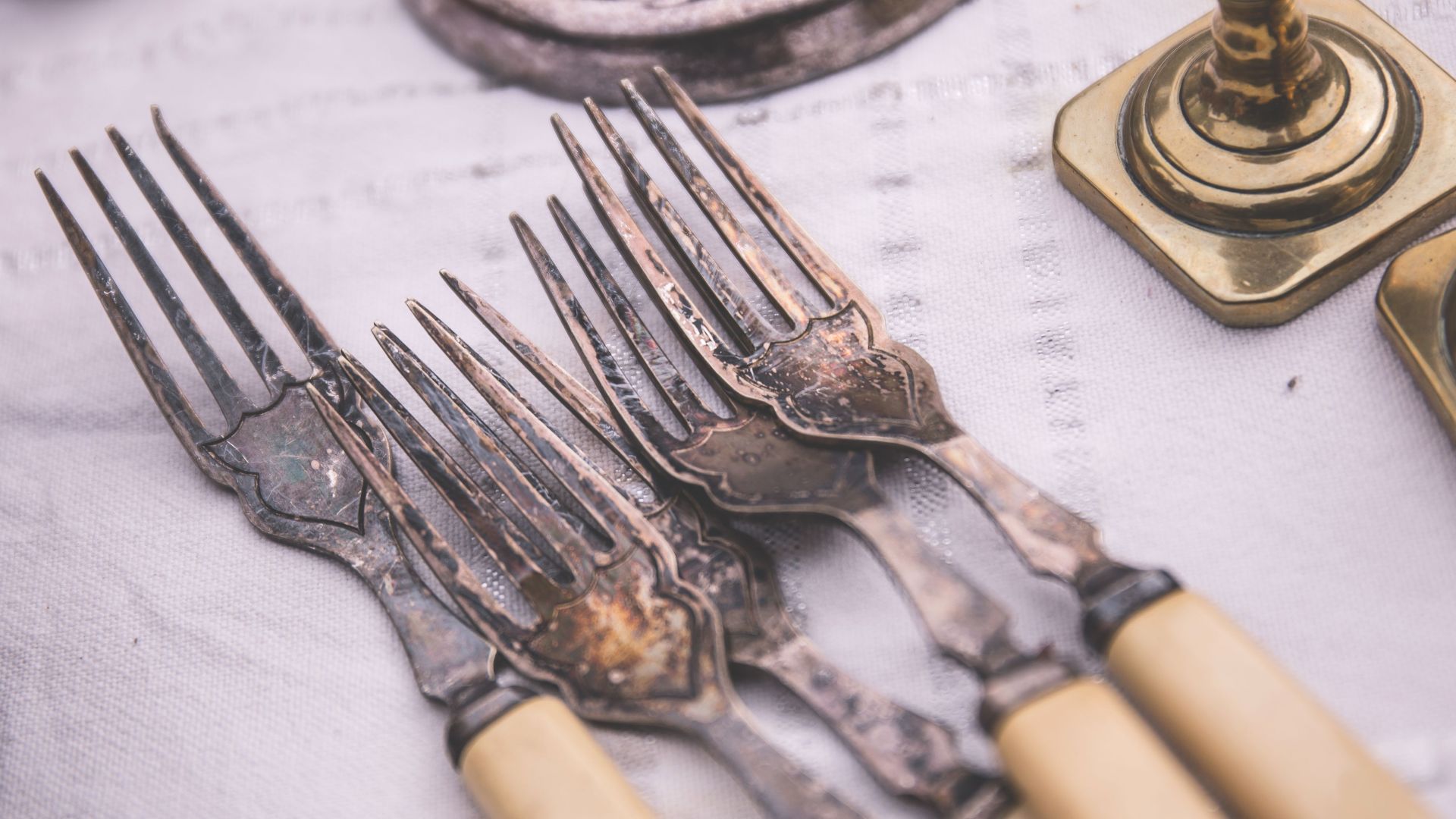 Close-up of elegant vintage silverware set on a classic white tablecloth, showcasing intricate design.