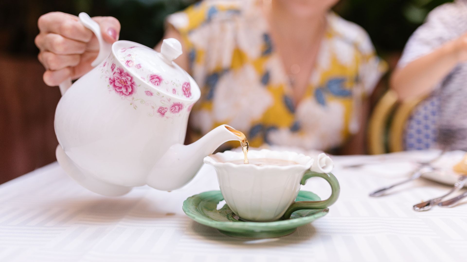 Graceful pouring of tea into a vintage cup, depicting a relaxing afternoon setting.