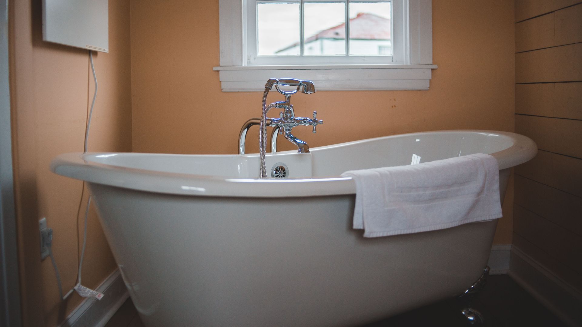 A classic clawfoot bathtub in a warm-colored bathroom with a window view.