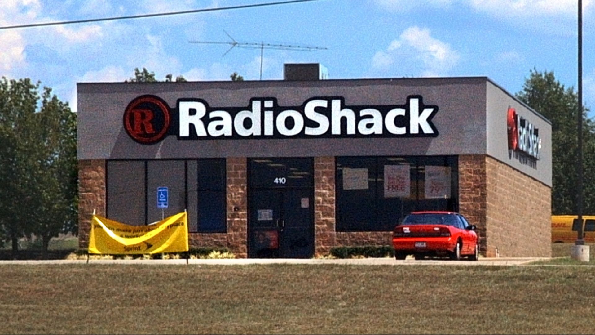 A free-standing RadioShack electronics store in Texarkana. Incidentally, a DHL delivery van is visible on the road behind the store.